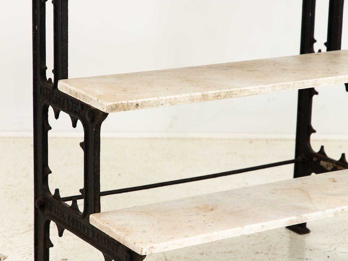 The vintage French black-painted cast iron plant stand exudes timeless elegance with its exquisite craftsmanship. It features three stone shelves, each showcasing unique veining patterns, adding a luxurious touch. With its sturdy construction and