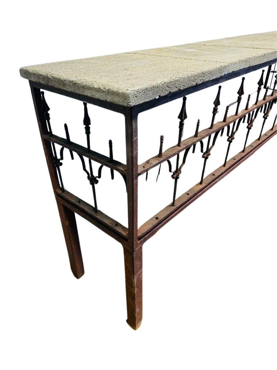 Questa consolle antica da giardino francese presenta una struttura in ferro arrugginito splendidamente invecchiato con intricati elementi decorativi, che emanano un'estetica industriale e consumata dal tempo. Il piano del tavolo è composto da lastre