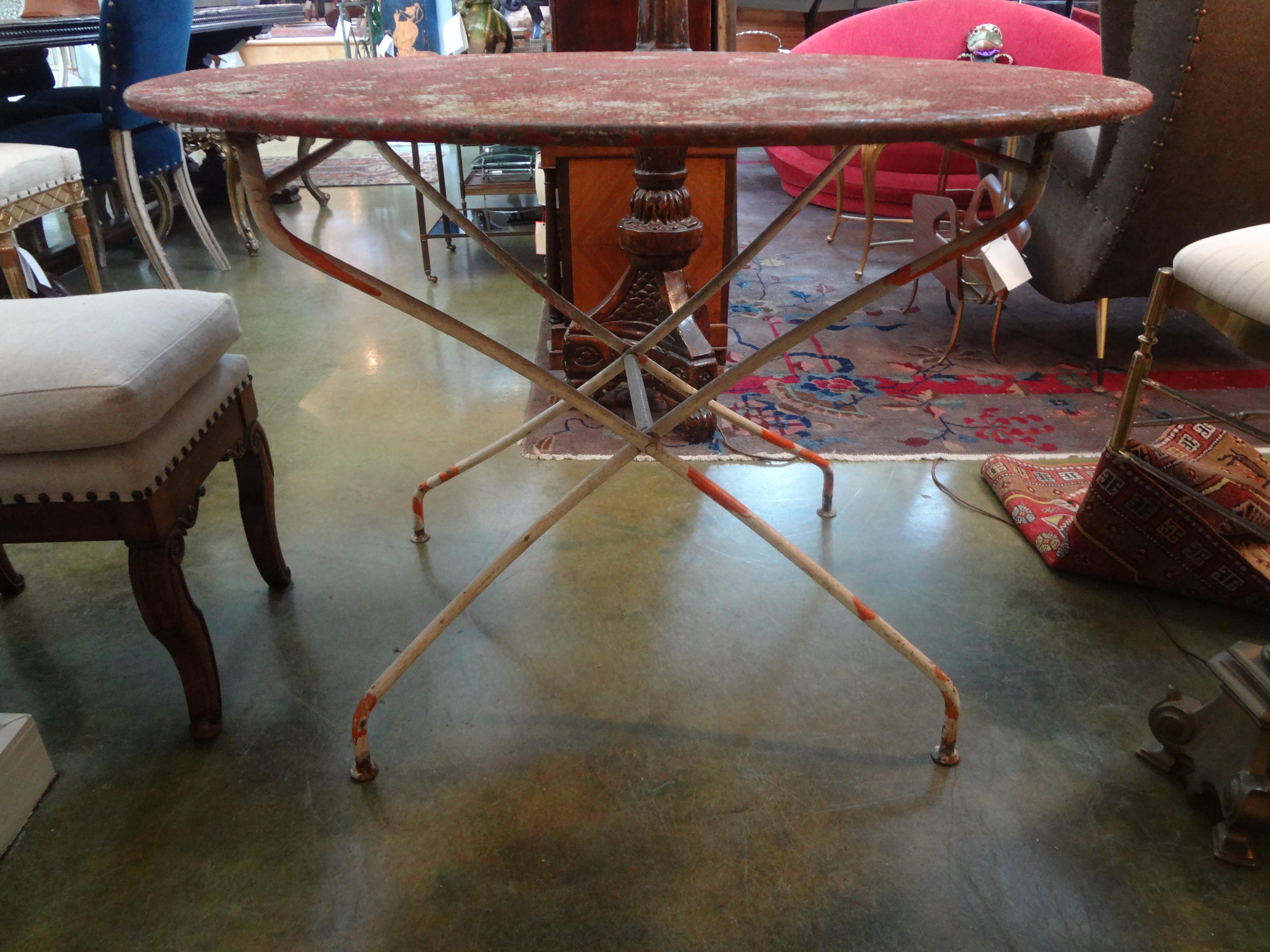 Gorgeous antique French folding iron garden table or bistro table with desirable chippy paint in soft orange-red and whites. This table would work well in an indoor garden room, family room or breakfast room.
