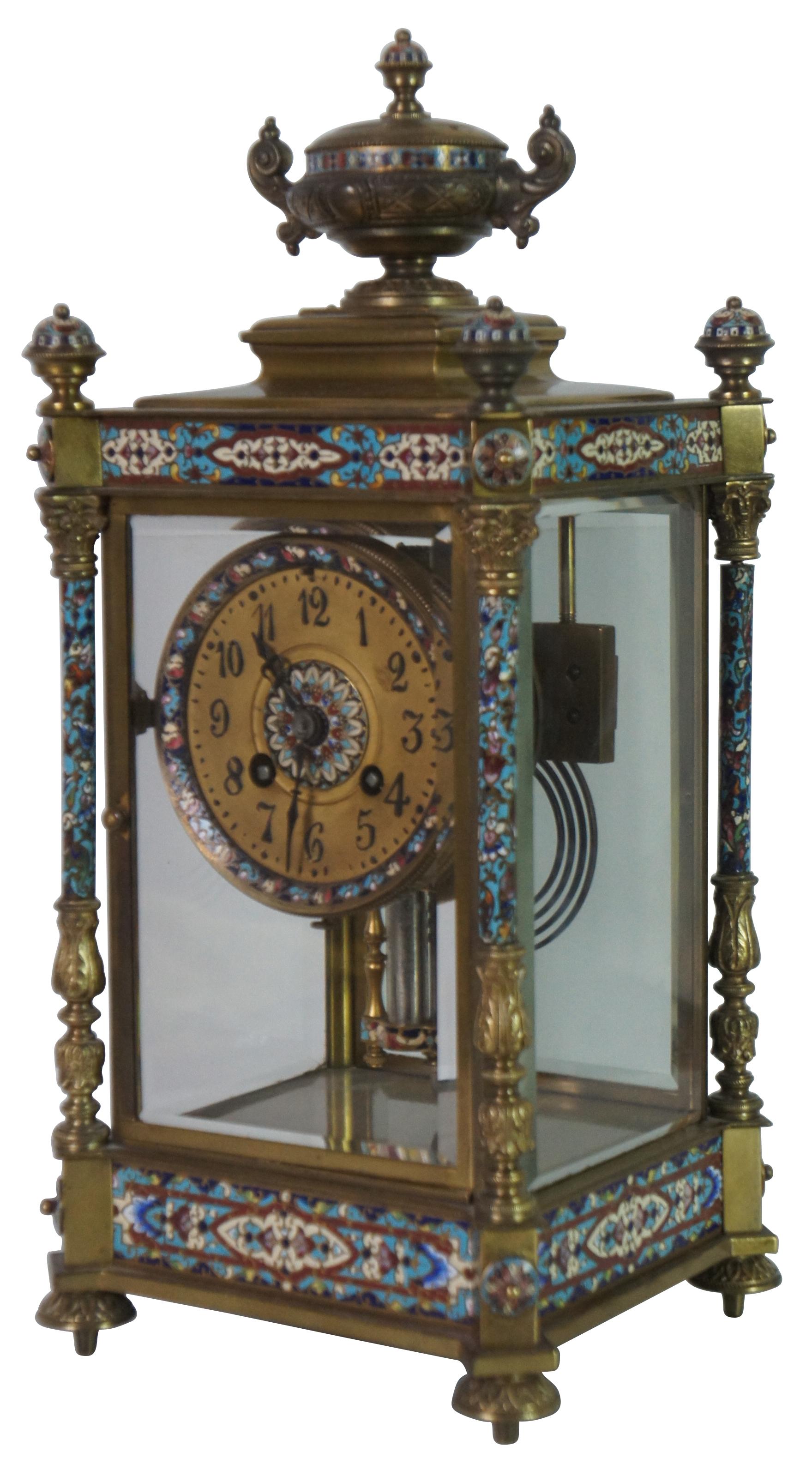 Antqiue late 19th Century French Japy Freres gilt brass enameled mantel clock featuring neoclassical styling with polychrome champleve enamel accents, four columns with spire finials, beveled glass sides and trophy vase topper. Stamped with Japy