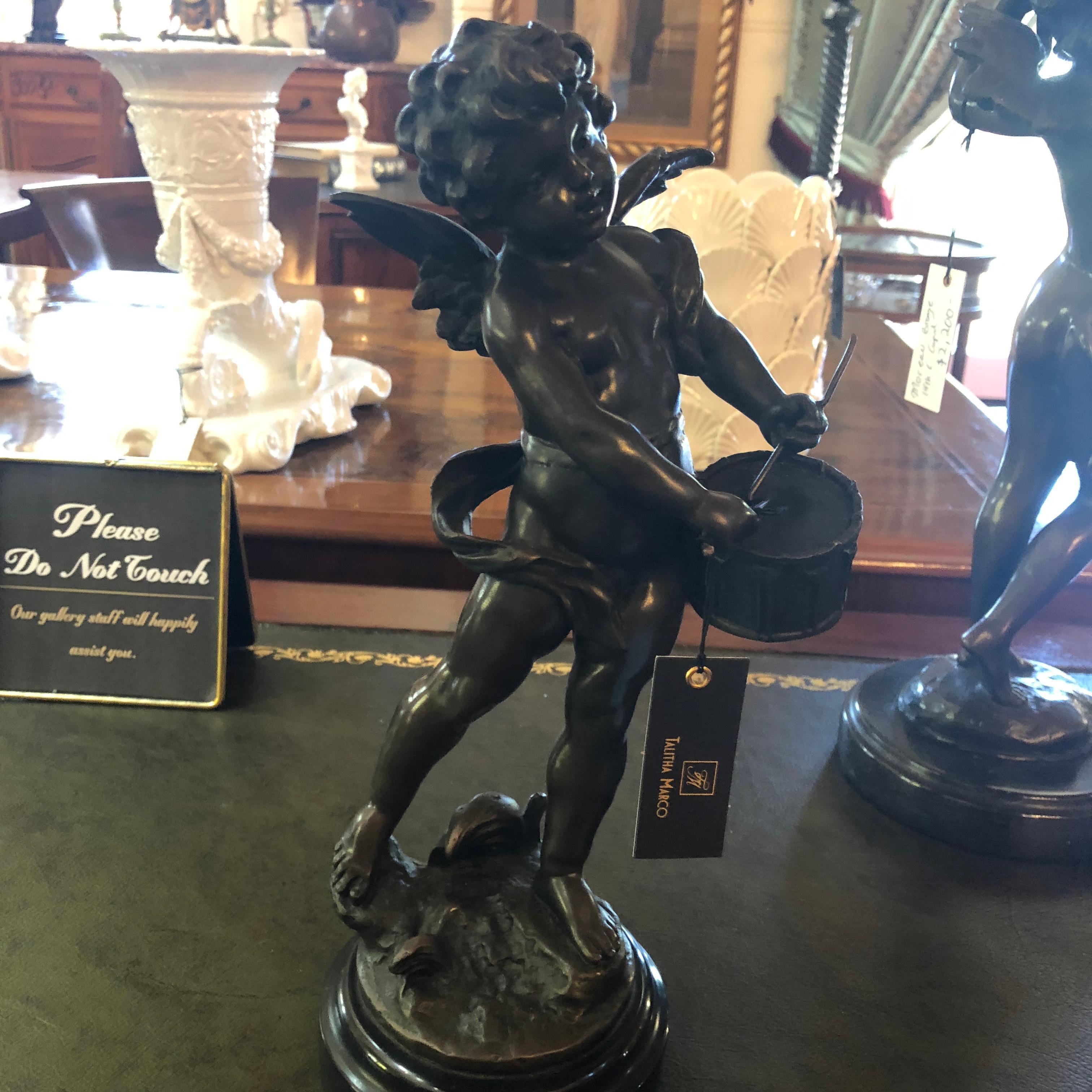 This L & F Moreau signed bronze winged cupid on marble base, features a delightful putti figure playing a drum with a cheerful expression. Standing at approximately 30cm tall, this charming figural statue, would be well suited as a Classic French
