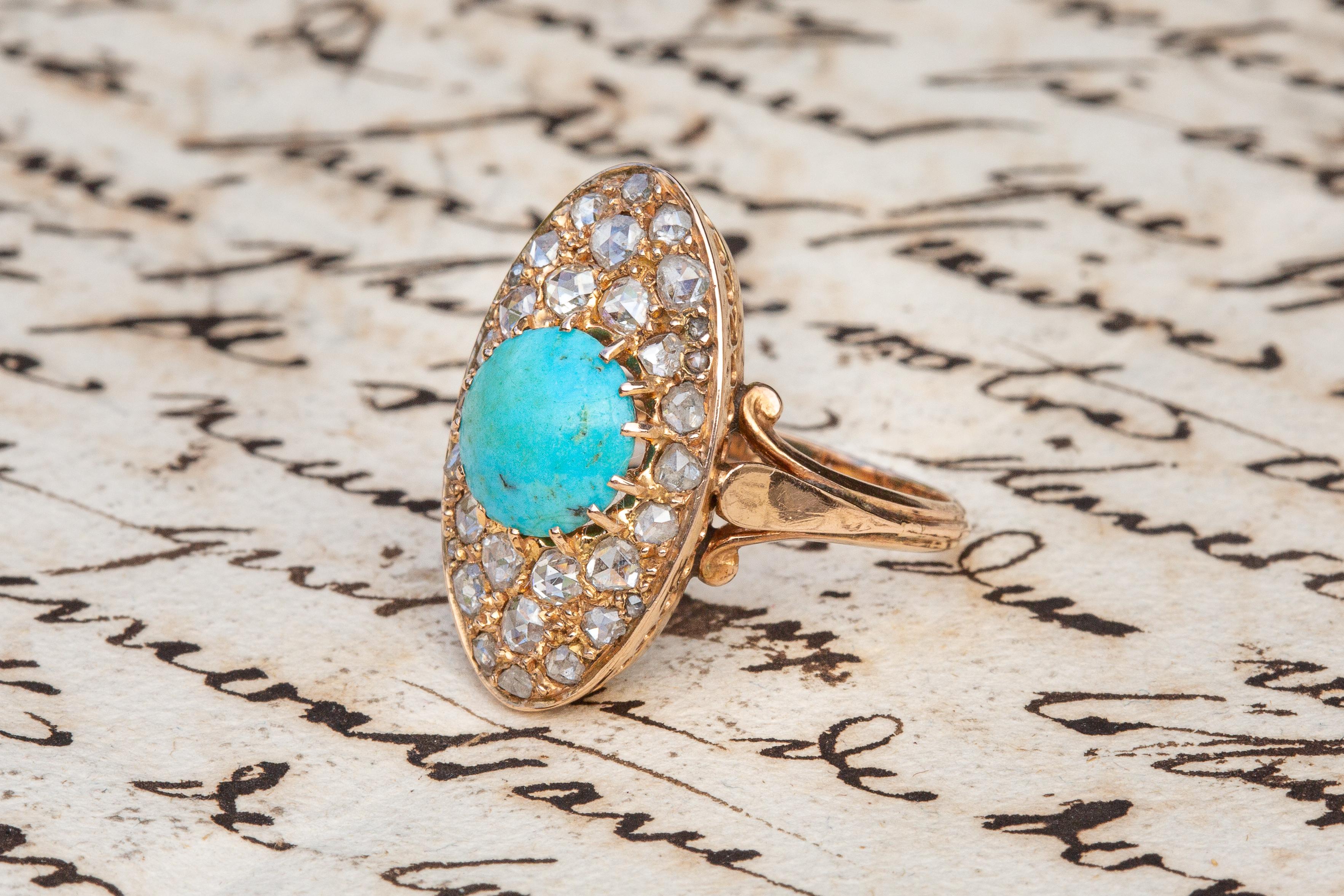 A stunning cluster ring dating to the late Victorian period circa 1880. This navette-shaped cluster is set with a large cabochon cut natural turquoise cabochon surrounded by 31 natural rose cut diamonds of varying sizes. The grooved D-shaped band is