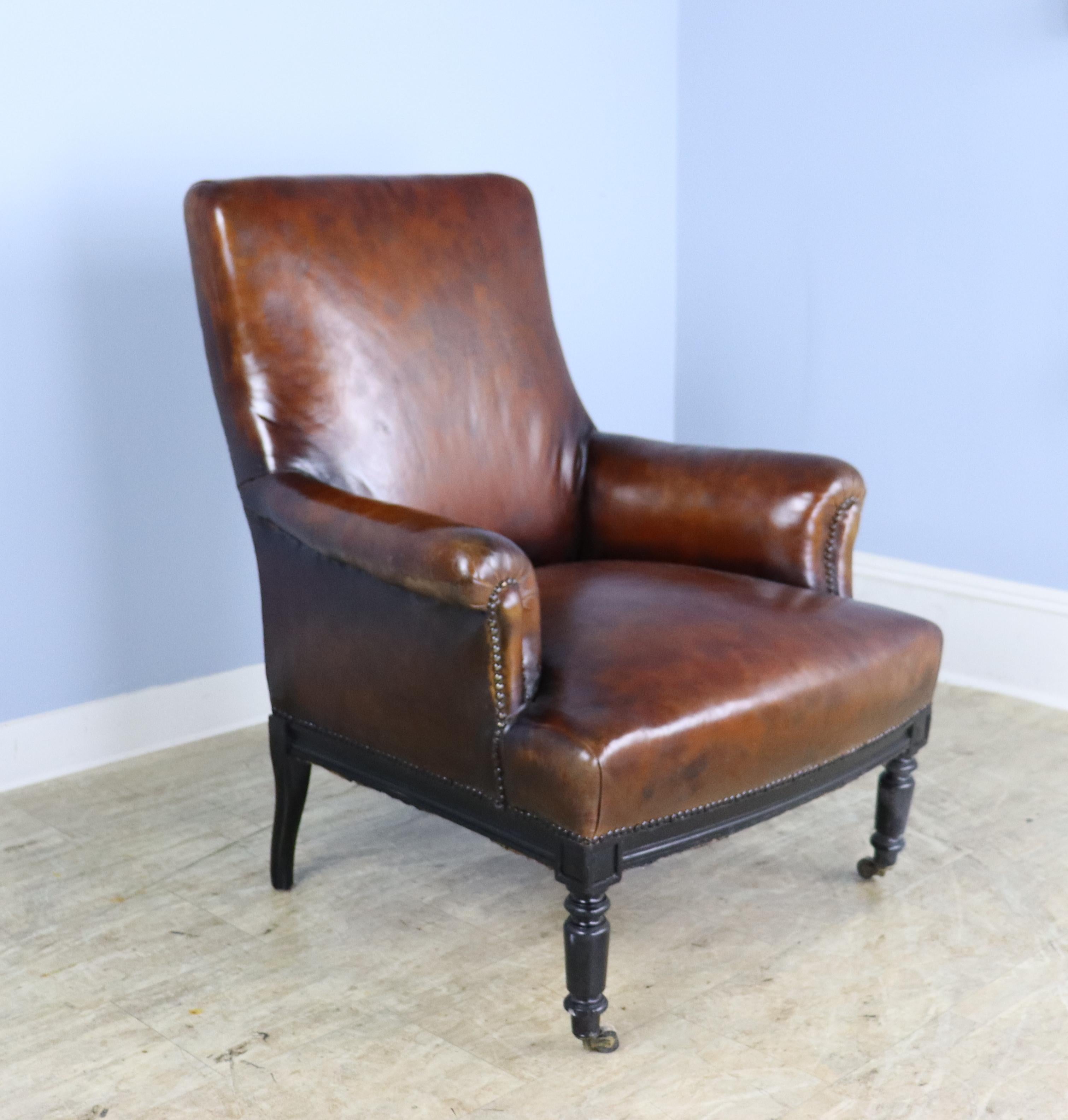 A handsome roomy armchair or clubchair in rich brown leather, in good condition for its age.  Nailheads are also in good shape.  Slightly reclined silhouette for comfoart and style.  