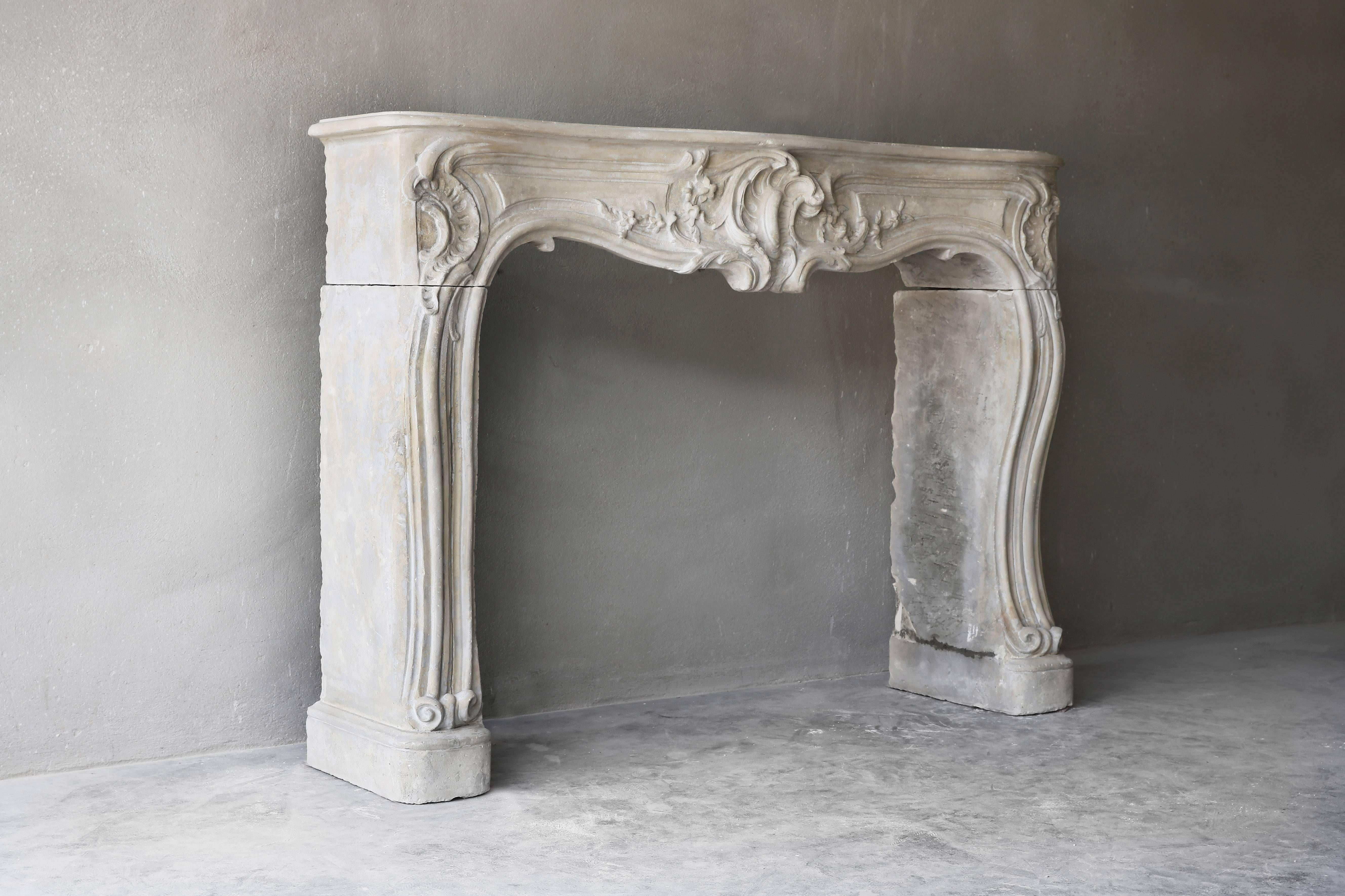 A beautiful antique chimney of French limestone in the style of Louis XV. This chimney comes from a chic Parisian apartment and has beautiful treatments on the front and legs. Characteristic of Louis XV are the scallops and decorations that make