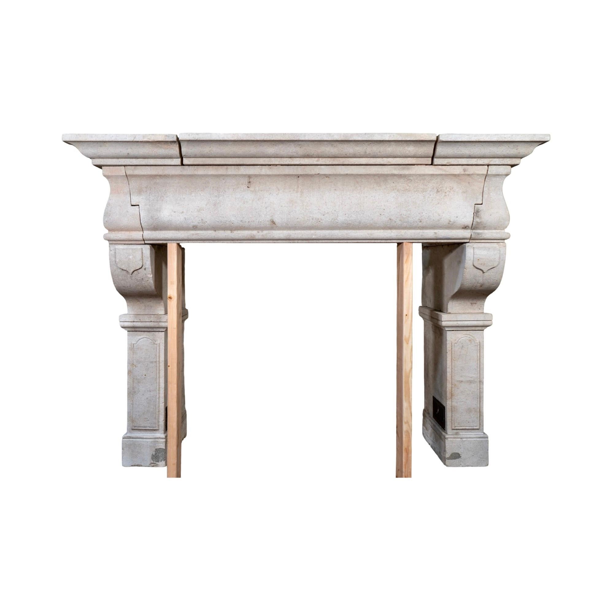 An antique 19th-century French mantel carved from limestone, with subtle detailing along its curved legs. Character wear and surface aging add to its timeworn charm. It also features original air vents at the base of each leg for functional airflow.