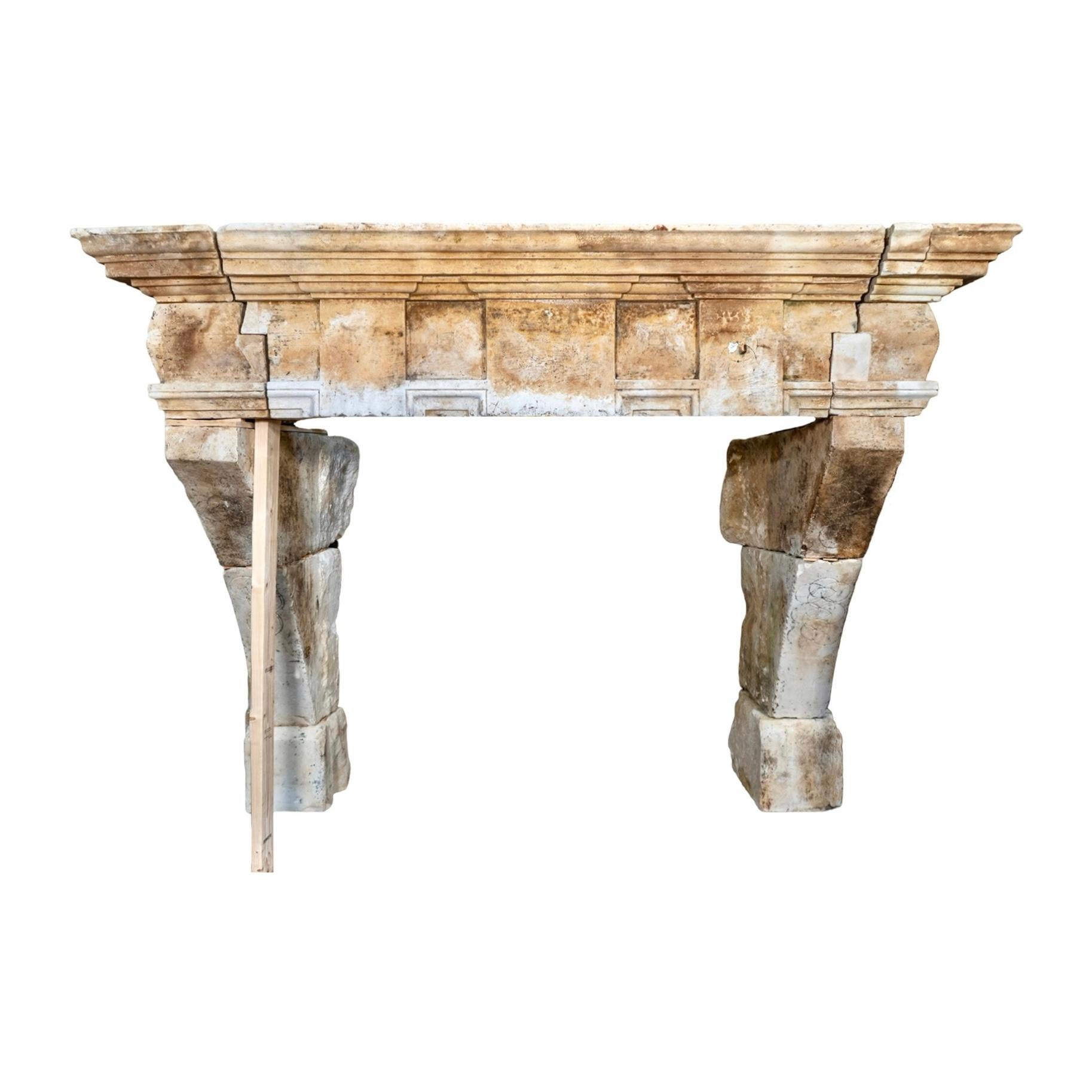 A rare architectural statement from 17th century France, this antique mantel is hand-carved from limestone and bears the patina and character of centuries past. The substantial form features bold, angular legs supporting a deeply molded shelf, all
