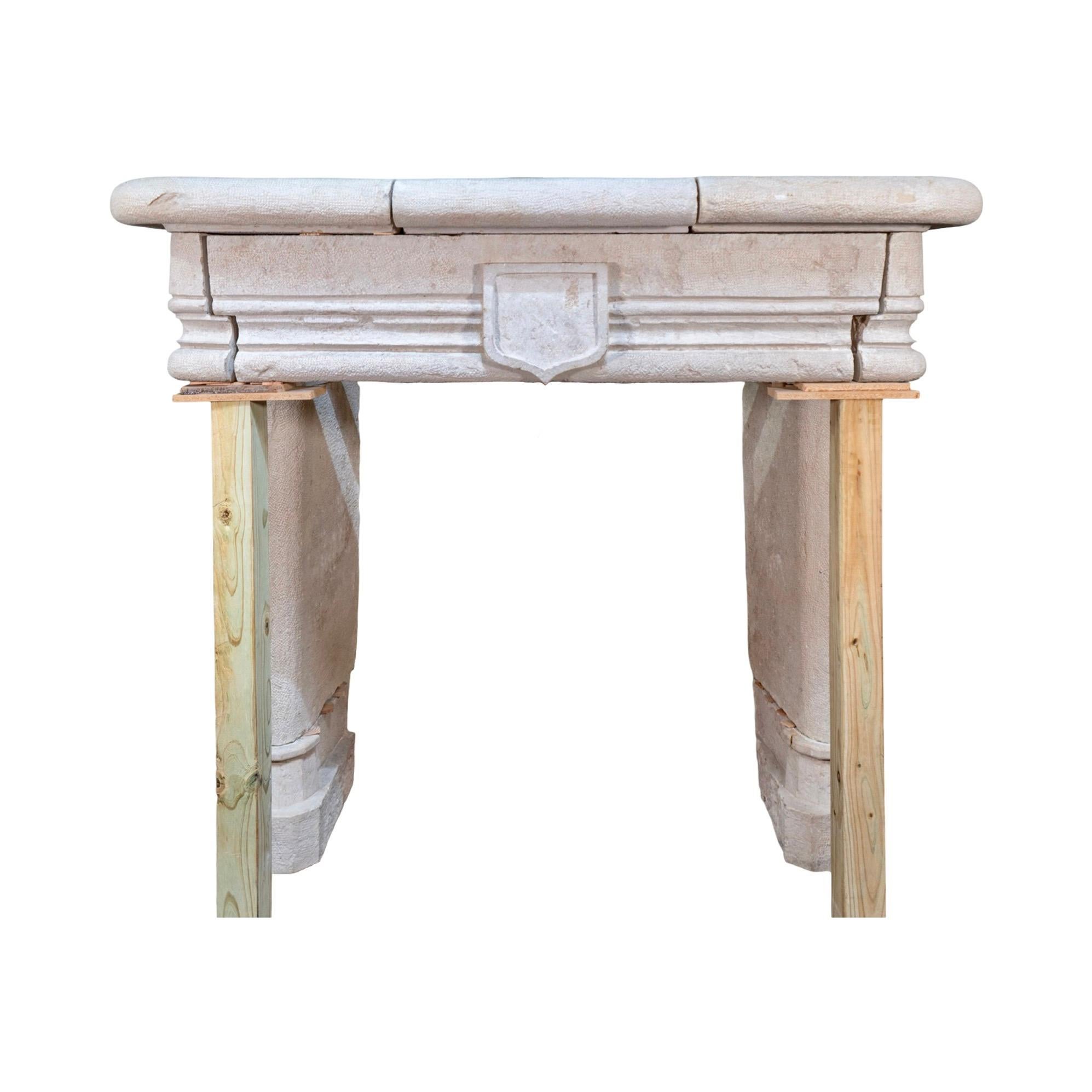 An elegant example of 18th century French craftsmanship, this antique mantel is carved from soft-hued limestone with subtle surface texture throughout. The profile features softened edges and rounded corners, contrasted by linear moldings that