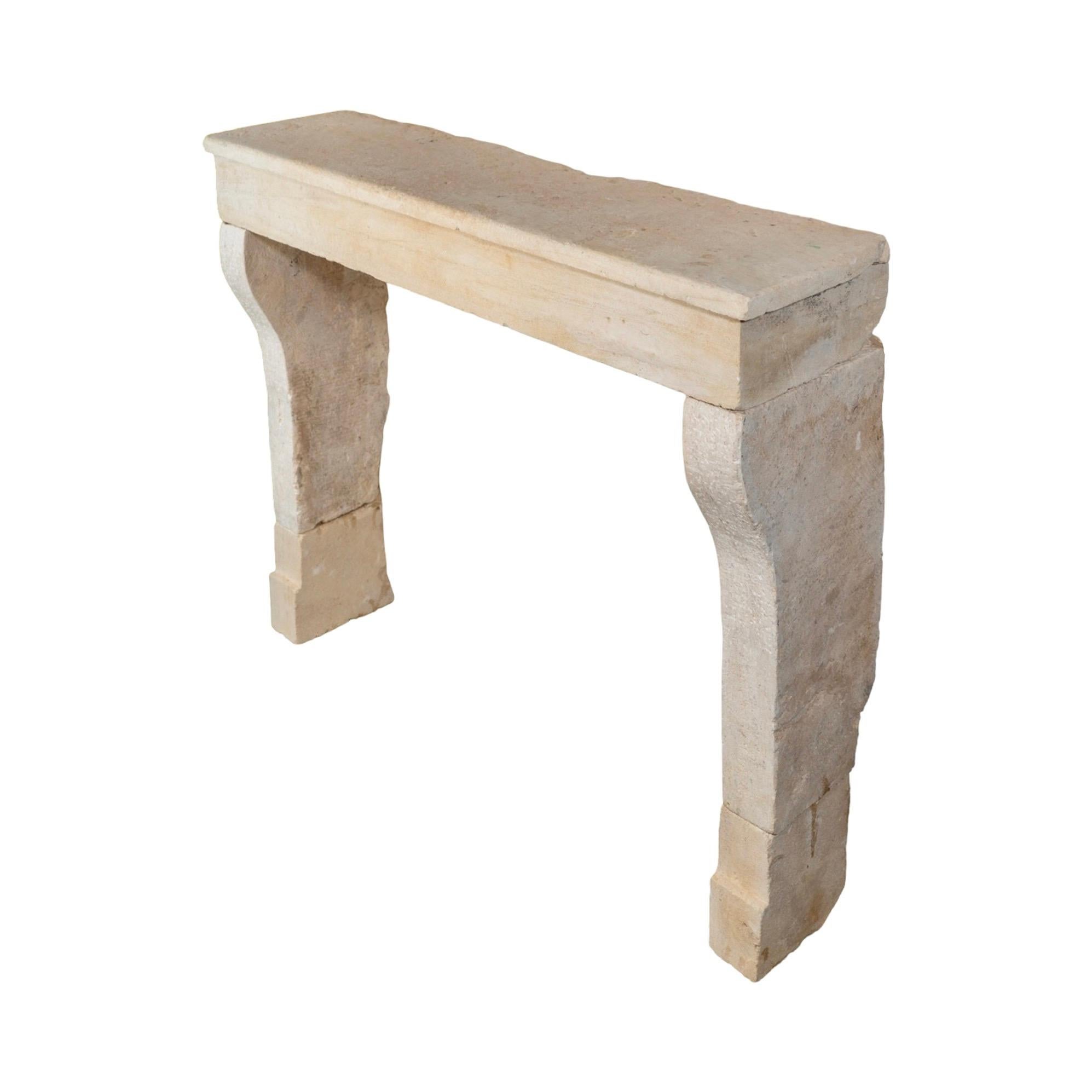 Sculptée dans la pierre calcaire française au XIXe siècle, cette cheminée de petite taille a une présence nette et discrète qui convient parfaitement aux espaces plus intimes. Les montants légèrement incurvés lui confèrent une silhouette douce et