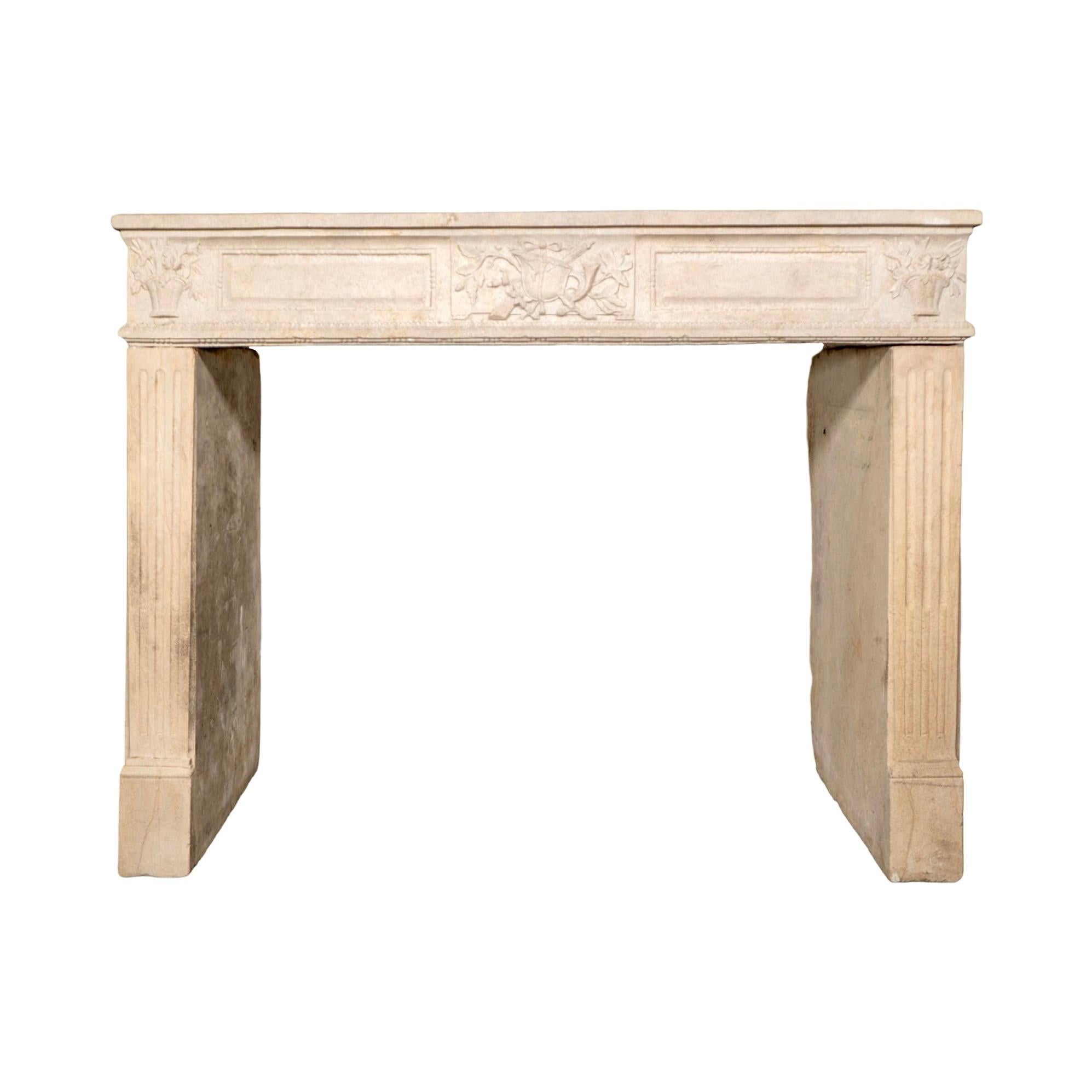 Un camino in pietra calcarea francese del XIX secolo con cesti floreali splendidamente intagliati agli angoli, un motivo centrale a fogliame e pannelli incorniciati sul fregio. Le gambe scanalate aggiungono simmetria e struttura, conferendo al pezzo
