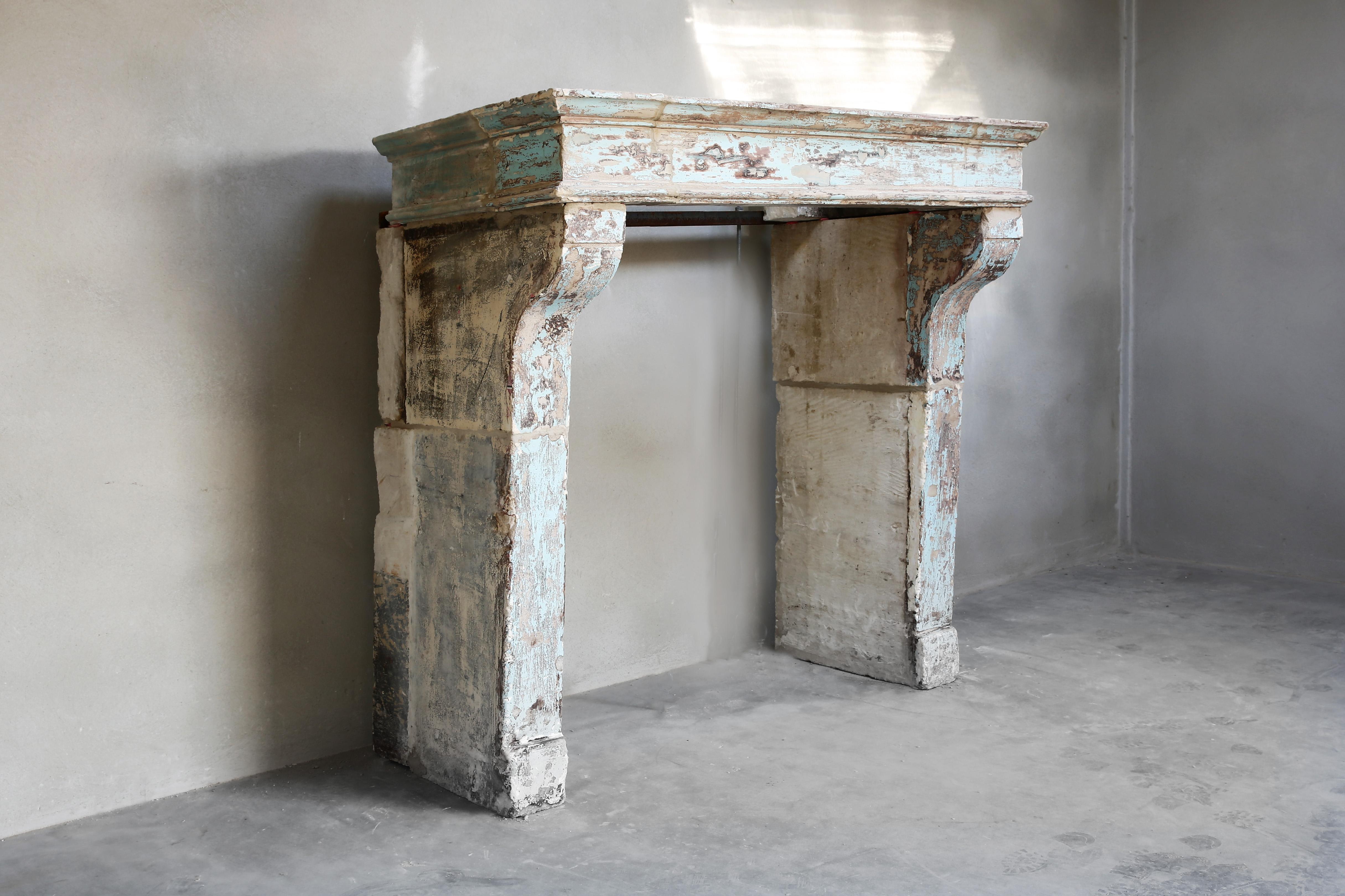 Beautiful patinated antique mantel fireplace of French limestone. The mantelpiece dates from the 19th century and is in the style of Campagnarde! A simple and sober appearance that fits within many interiors. The old blue paint or patina makes this