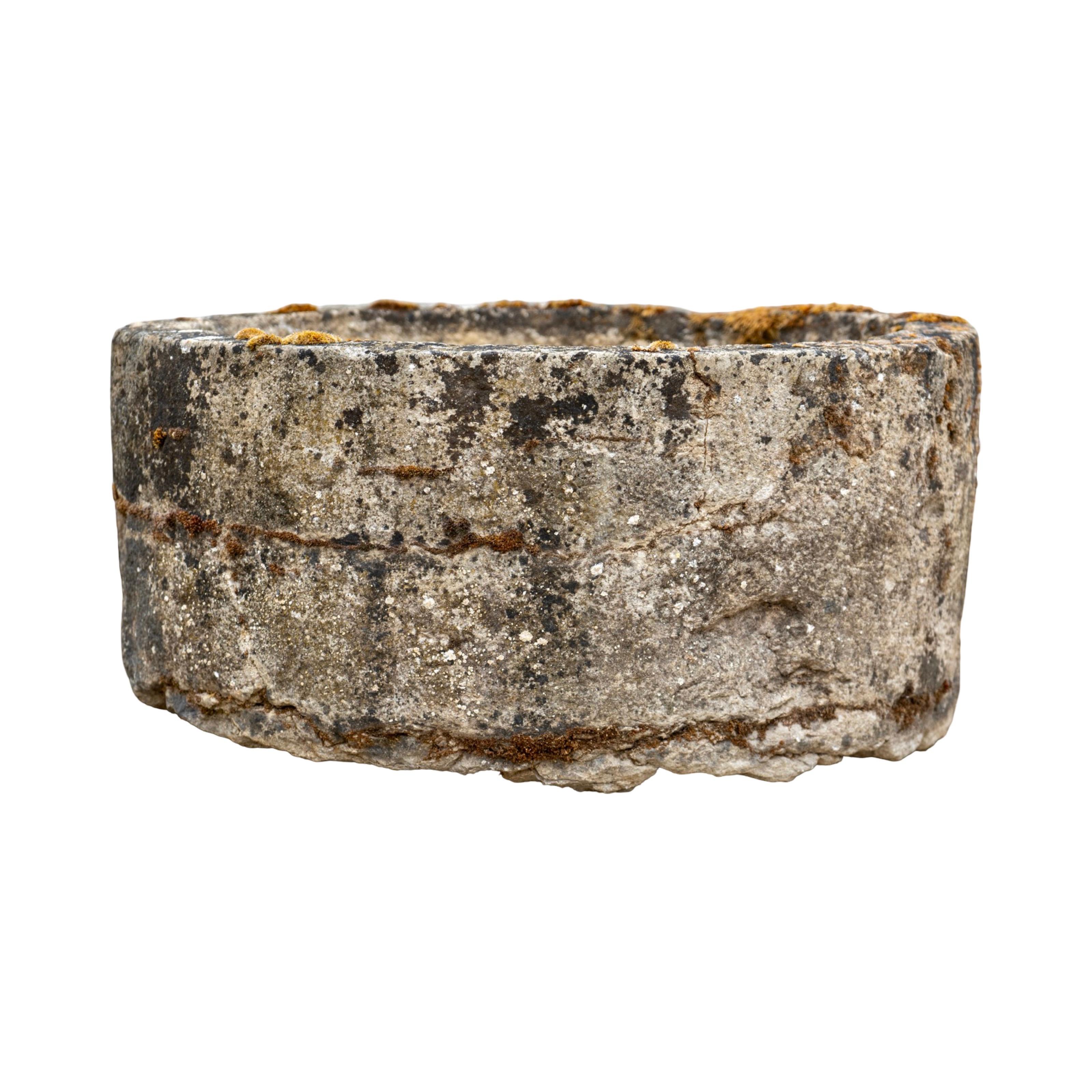 A small circular trough carved from limestone, France, 18th century. Its low, rounded form shows centuries of weathering and patina, with one original drainage hole intact. Perfect as a garden planter, water feature base, or decorative accent,