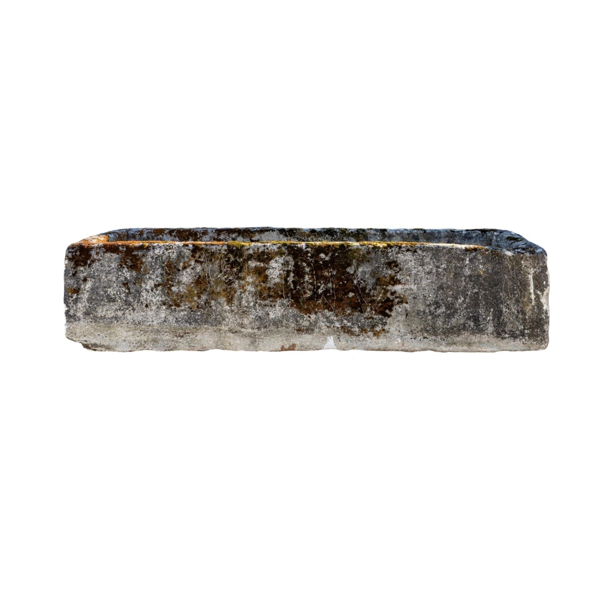 Un antico abbeveratoio in pietra calcarea del XVIII secolo, recuperato in Francia, ha un'ampia forma rettangolare ed emana un carattere senza tempo grazie alla sua ricca patina e all'usura naturale, che riflette la sua storia. Progettato con cura, è