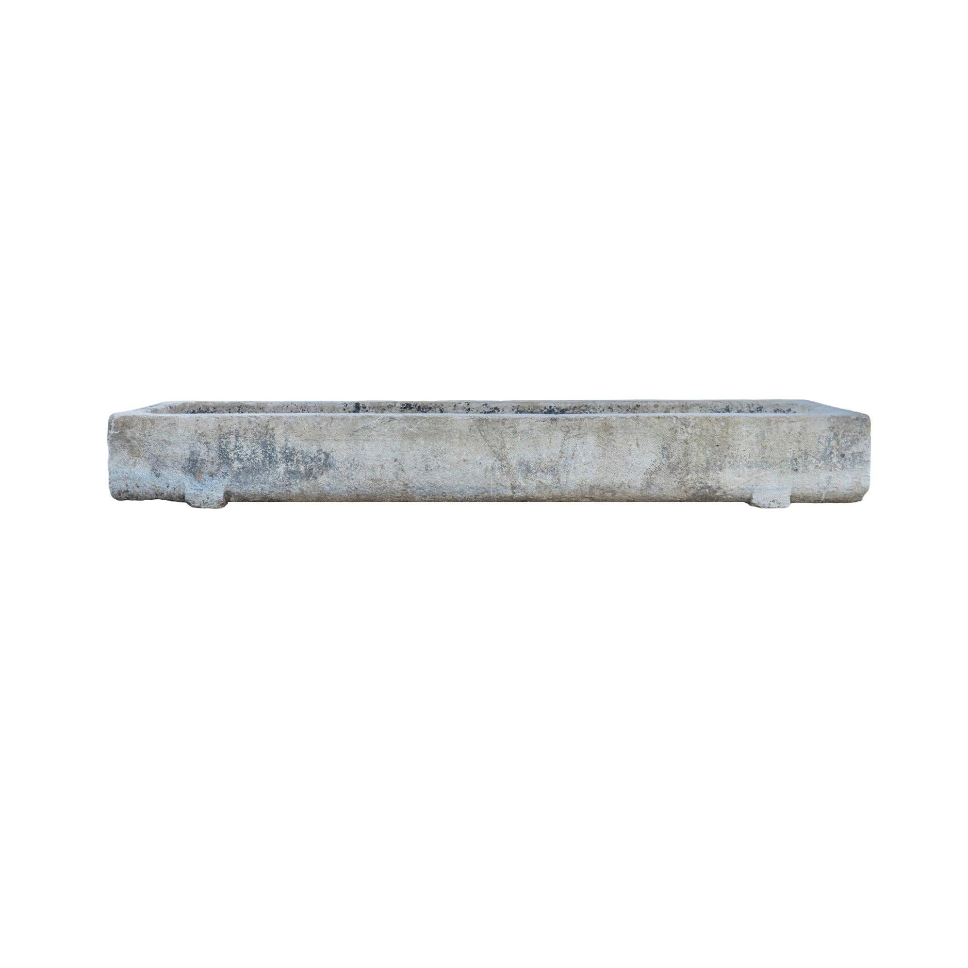 Un antico abbeveratoio in pietra calcarea del XVIII secolo proveniente dalla Francia, caratterizzato da un design largo, lungo e stretto. La sua patina splendidamente invecchiata e il suo carattere segnato dalle intemperie raccontano il tempo e la