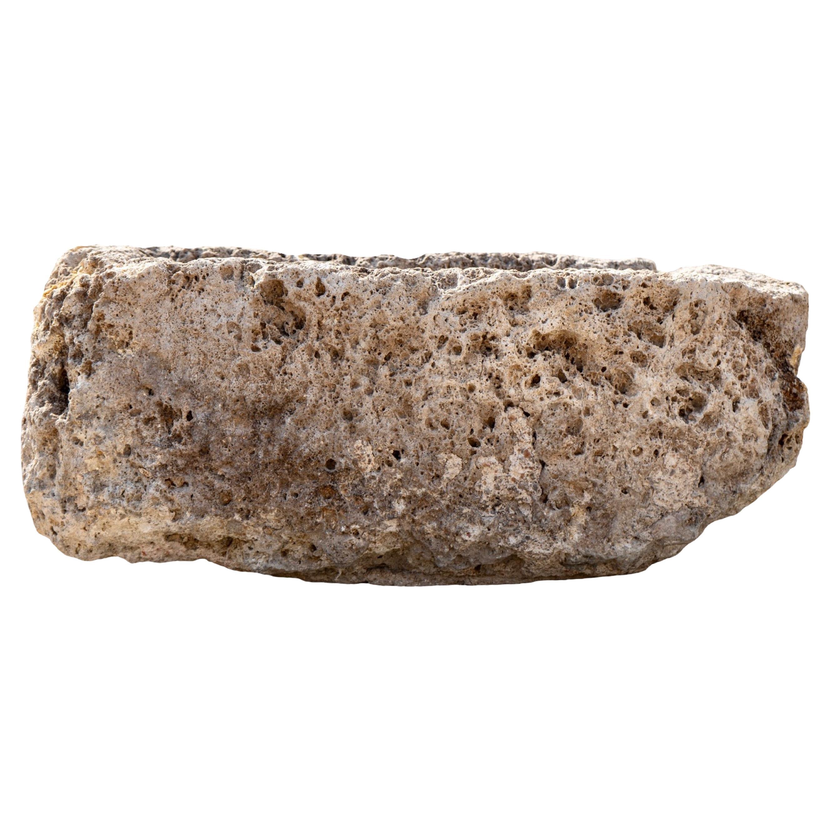 Questo piccolo abbeveratoio antico, scolpito a mano in Francia in pietra calcarea all'inizio del XVIII secolo, è al tempo stesso recuperato e ricco di storia. La sua superficie in pietra porosa mostra una struttura e un carattere notevoli, con vuoti