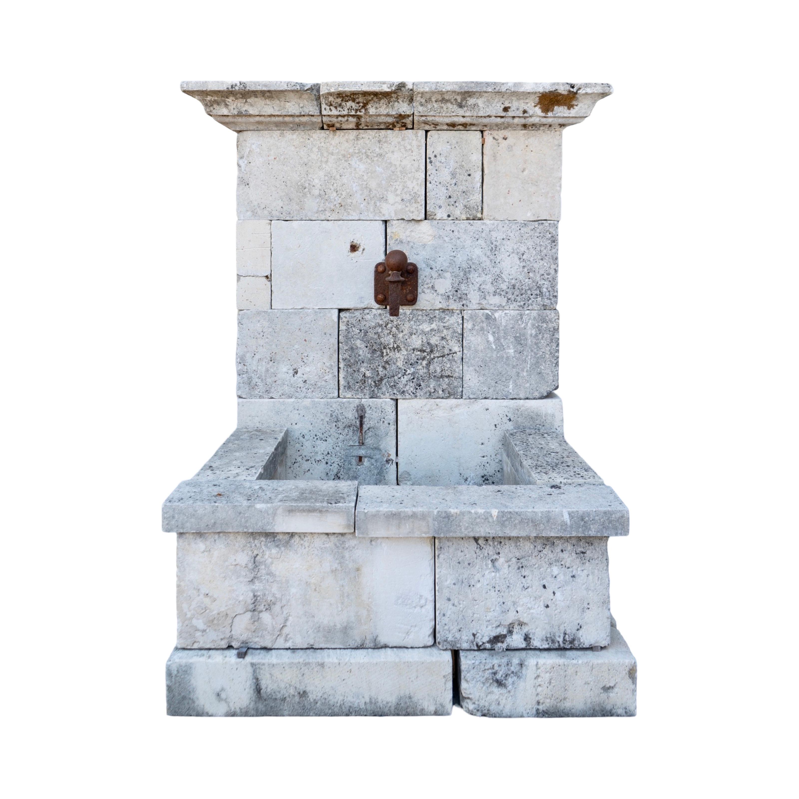 Una exquisita fuente mural francesa de 1890, tallada a mano en piedra caliza, que muestra una artesanía atemporal. Esta fuente antigua cuenta con una pila de generosas dimensiones para alojar el rebosadero de agua e incluye un orificio pretaladrado