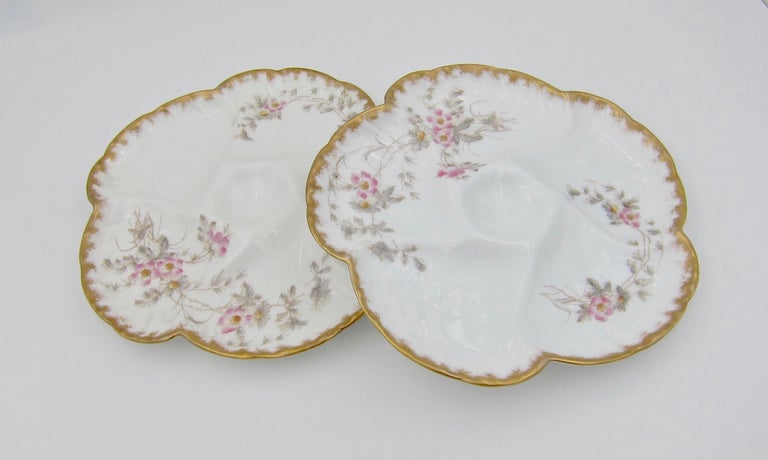A pair of antique French porcelain oyster plates from Société Gérard, Dufraisseix and Morel (formerly Charles Field Haviland) of Limoges, France. The molded 'Wave' pattern design includes five wells for oysters over ice surrounding a smaller,