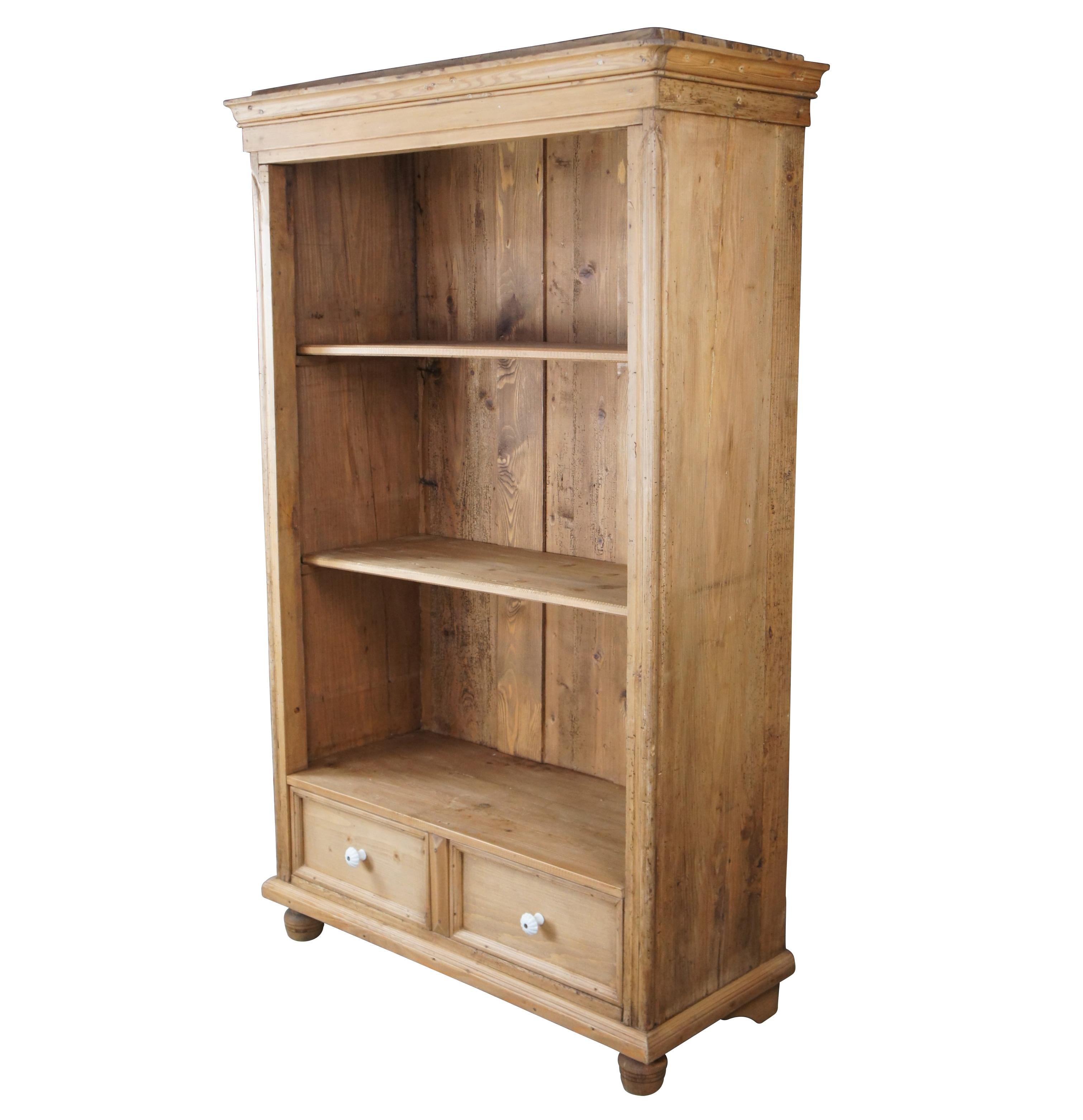 French Louis Philippe style bookcase, circa 1860s. Made from pine with a paneled back, removable shelves and lower dovetailed drawer with porcelain handles. Supported by turned peg feet. Great for display of books or collectibles. The cabinet was