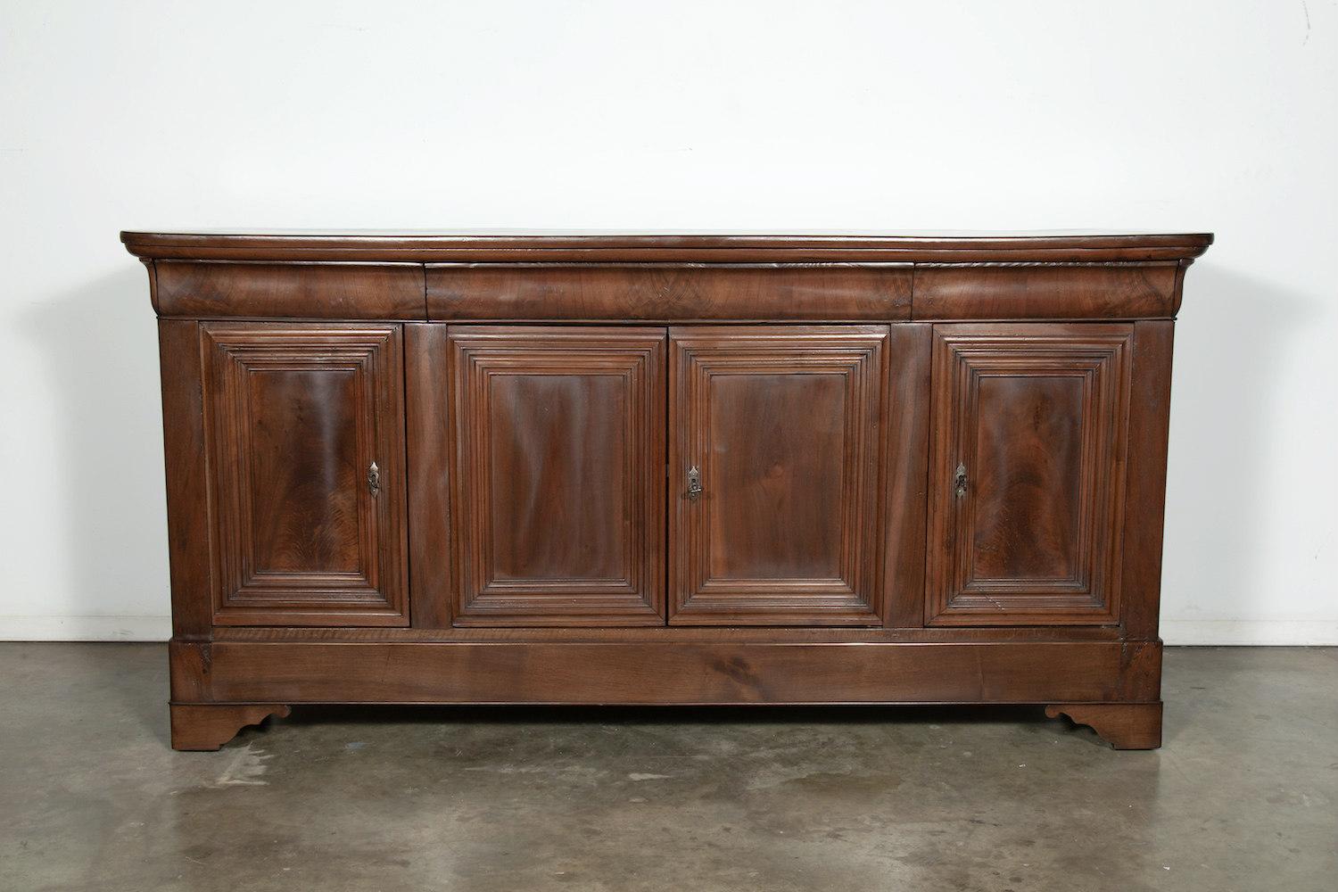 French Louis Philippe enfilade buffet of solid walnut with a bookmatched walnut front, having three doucine drawers over four paneled doors. Resting on shaped bracket feet. The shapely feet have a distinct shape designed to be seen from all sides