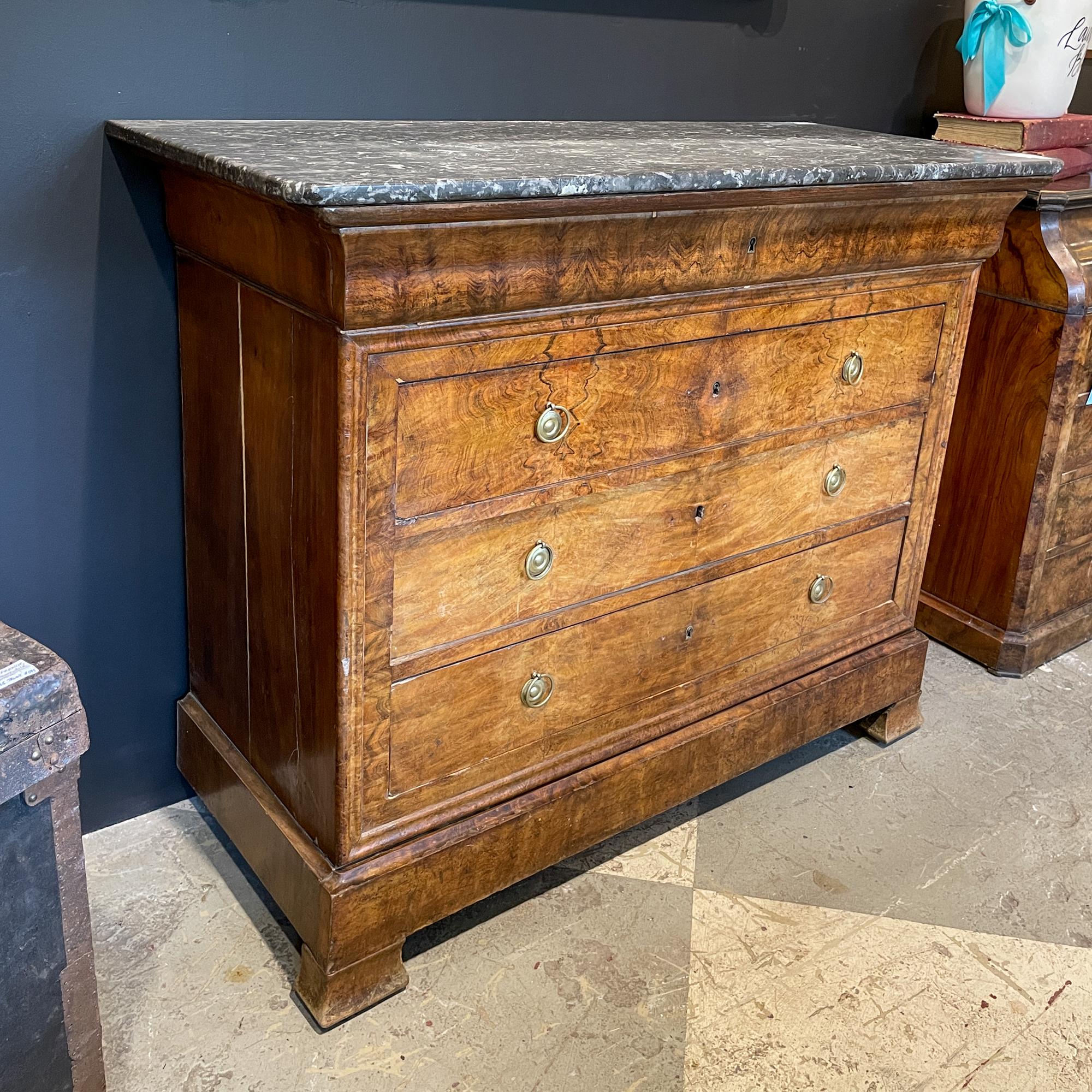 This is an antique French Louis Philippe mahogany veneer commode with five drawers and a Belgian marble top. The main body of the chest has three drawers, as well as a narrow drawer at the very bottom (between the legs) and the very top. The bottom