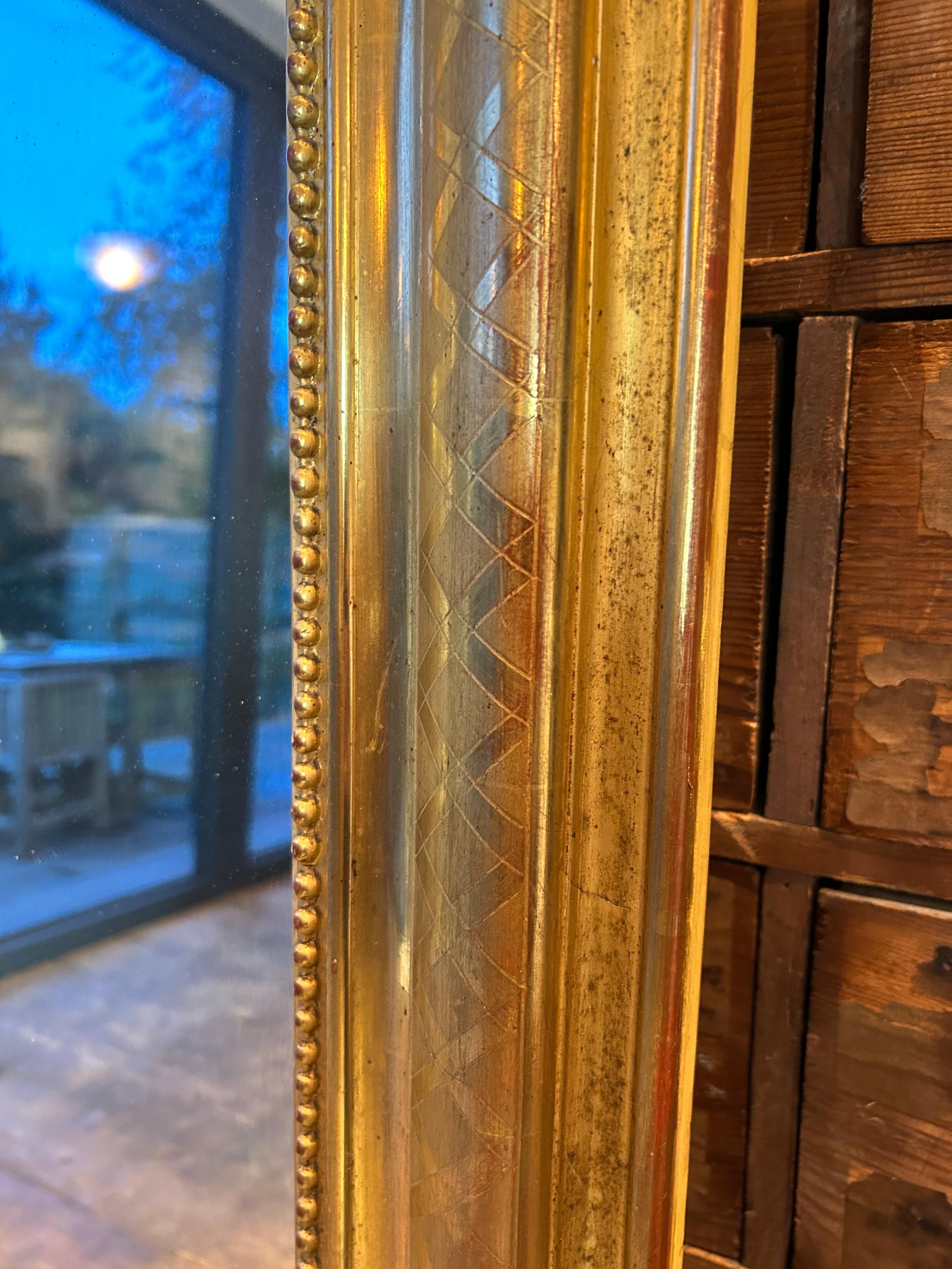 Louis Philippe water gilded mirror, cross etched border decoration, with inner bead moulding and finely carved crest, retaining its original burnished water gilding with slight rub through to the red bole, also the mirror glass and back boards are