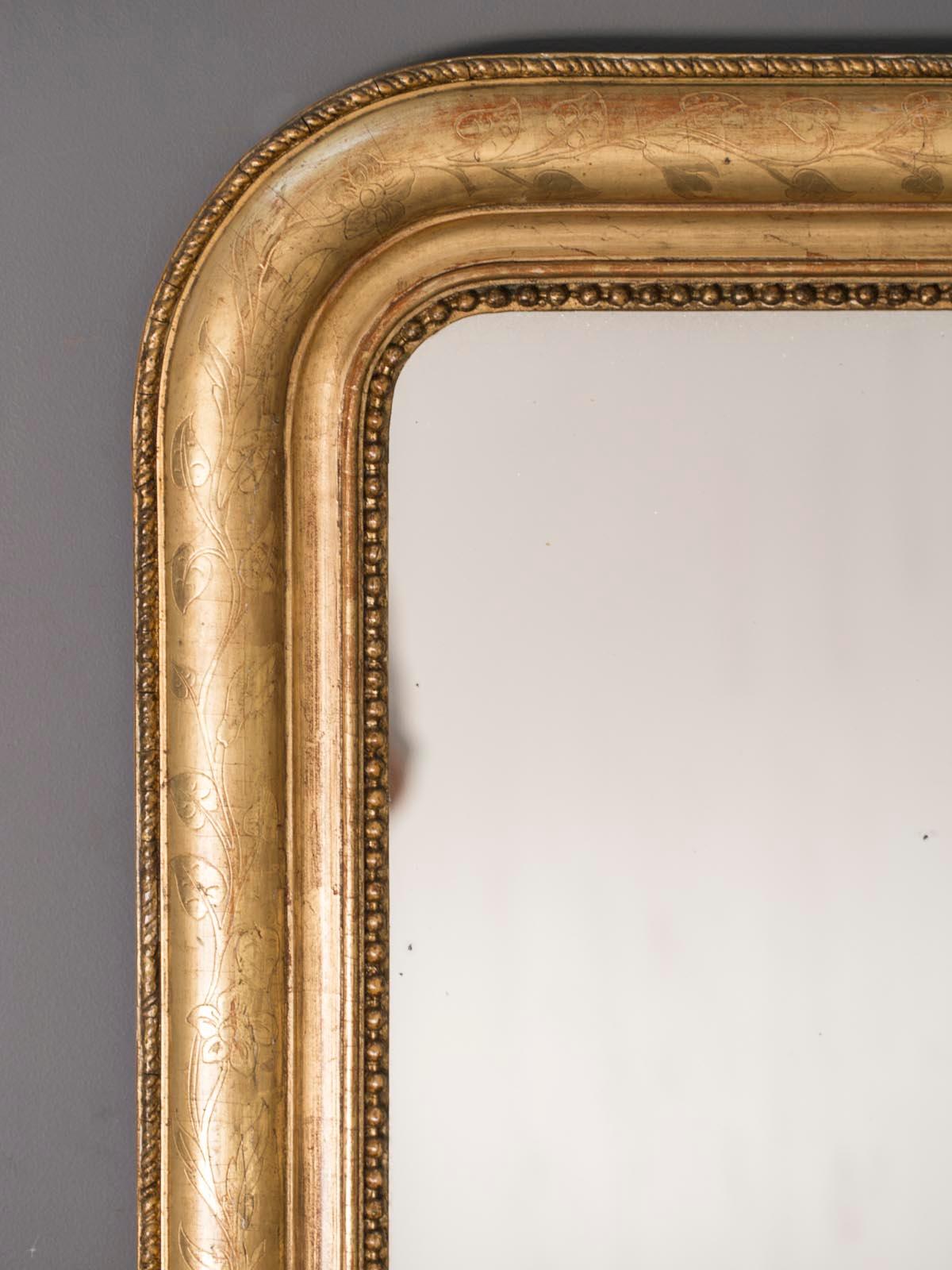 A classic antique French Louis Philippe gold leaf mirror from France, circa 1885 with the original mirror glass. The wonderfully elegant shape of this French mirror with its rounded shoulders and simple rectangular base is offset with the decorative