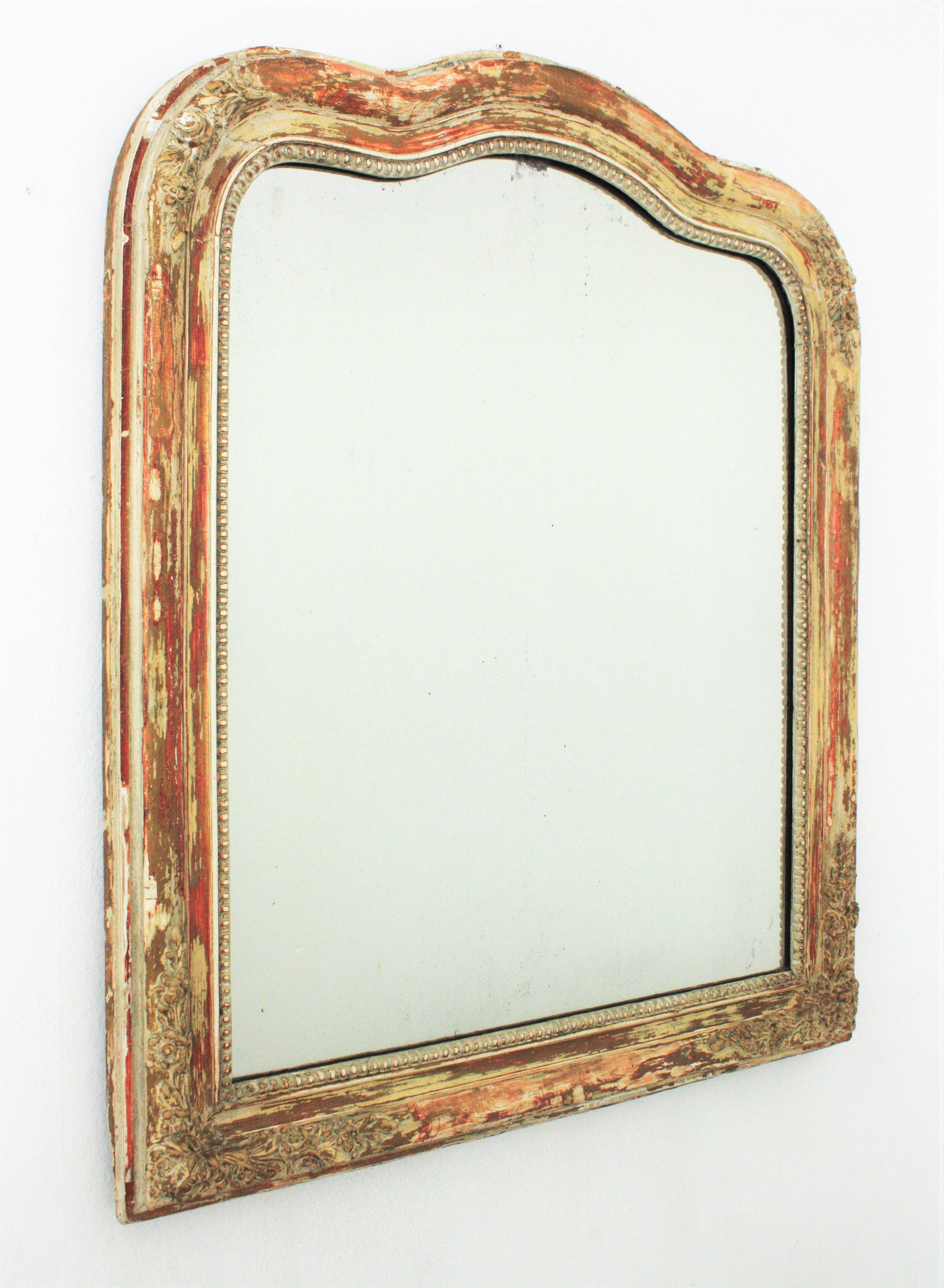 Louis Philippe mirror with finely carved floral details and terrific patinated parcel-gilt finish. France, circa 1840.
The frame has parcel-gilt gold leaf accents and an amazing patina showing different coats of paints in shades of brown, orange