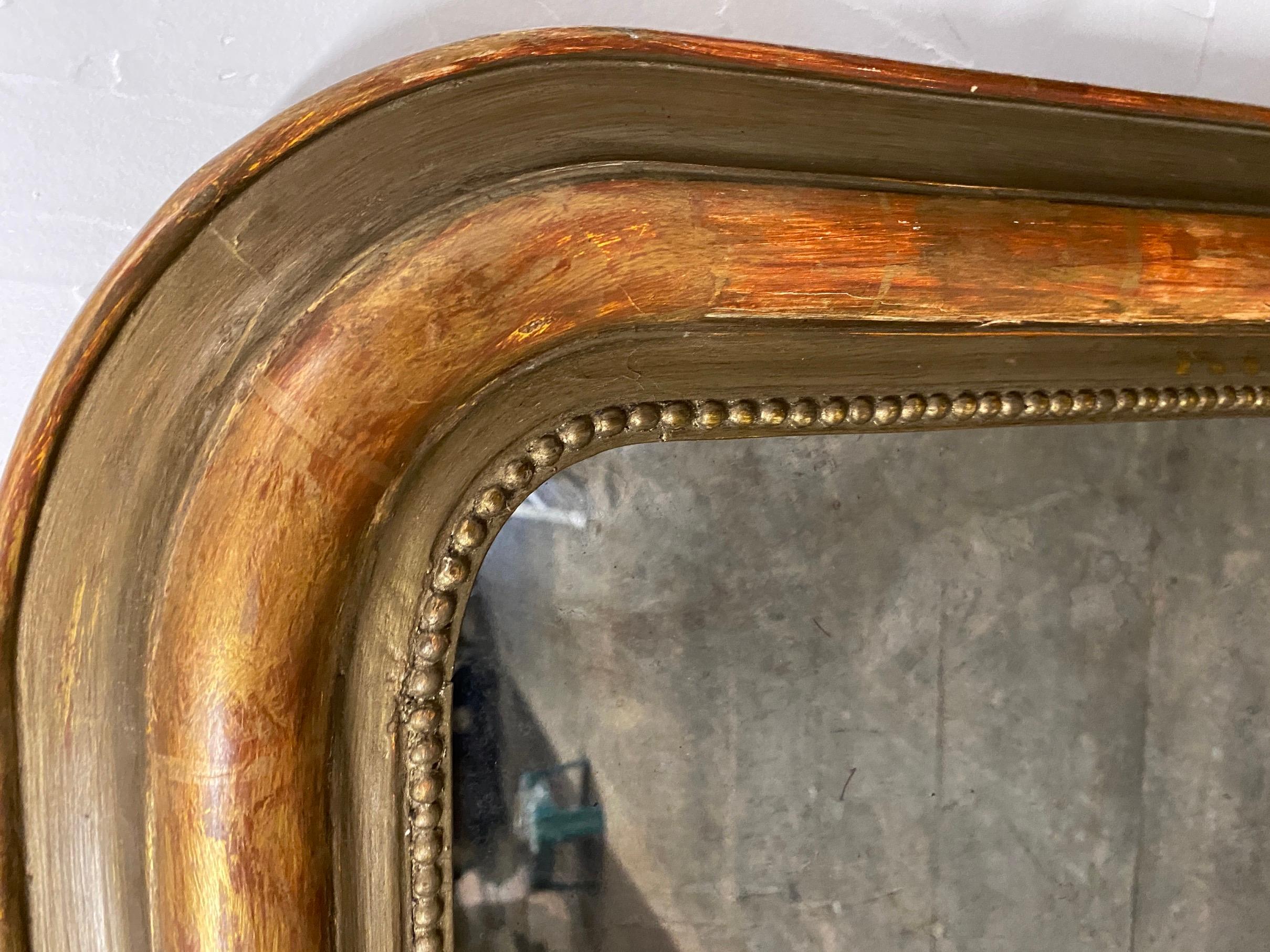 Lovely classic Louis Philippe mirror originally gold gilt but much has worn off. Red bole layer is apparent and adds a lovely complement to the remains of the leaf finish. Mirror has a carved beaded pearl detail that runs along the perimeter of the