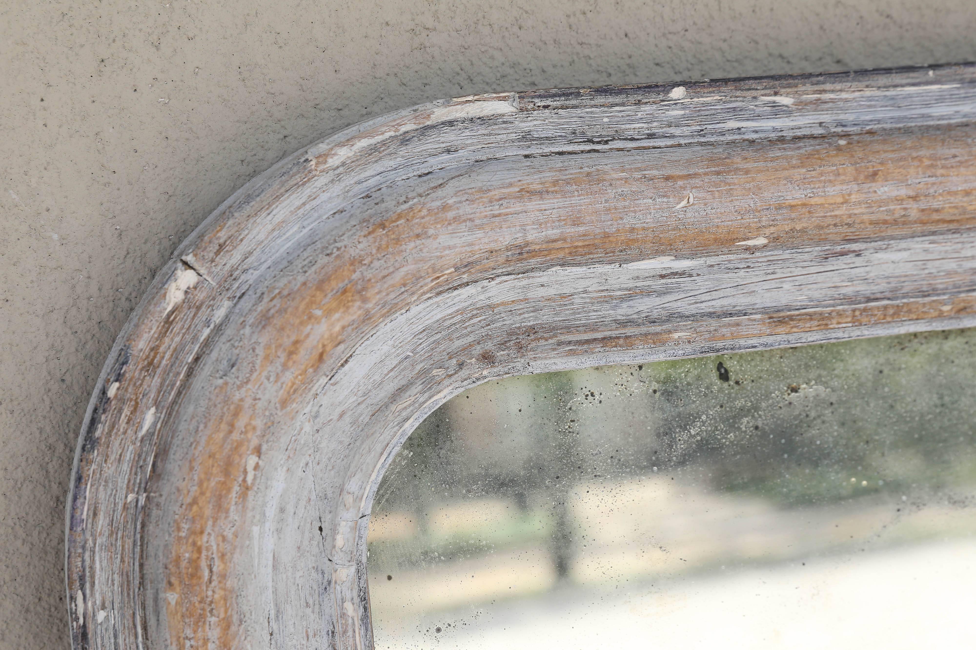 This Louis Philippe mirror is the perfect size for a vanity. The carved and once hand-gilt frame has been painted in a distressed grey finish, although it is unknown when this finish was added. Uncovered in France, this wonderful mirror has visible