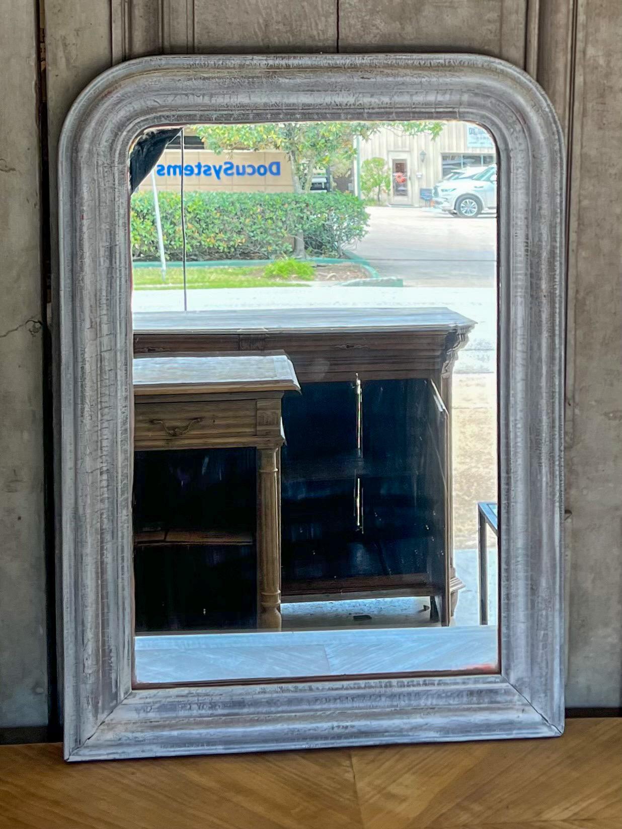 Early Louis Philippe Mirror imported from Northern France, this piece has a lovely greige distressed finish in tones of grey and white. Hand carved and backed in wood, this piece measures 24.75