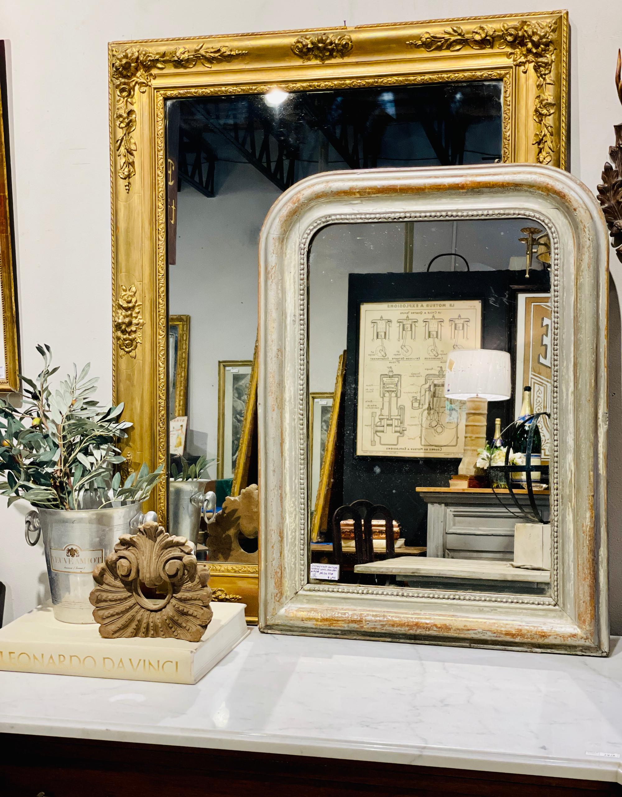 A beautifully distressed antique French Louis Philippe Mirror with silvery-gilt frame, beaded detail and original glass. Ready to hang on a wall, leaned on a mantel or console, this small mirror has gold and russet details peeking through the