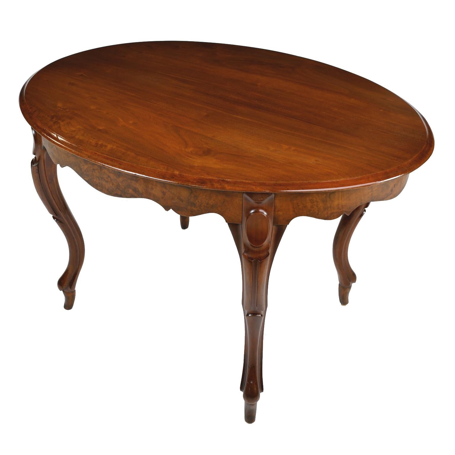 A fine Louis Philippe salon table with oval top and scalloped apron resting on four graceful carved cabriole legs. Top and legs are made of solid mahogany, with the apron made of burl walnut. France, circa 1840. Makes a handsome small dining table,