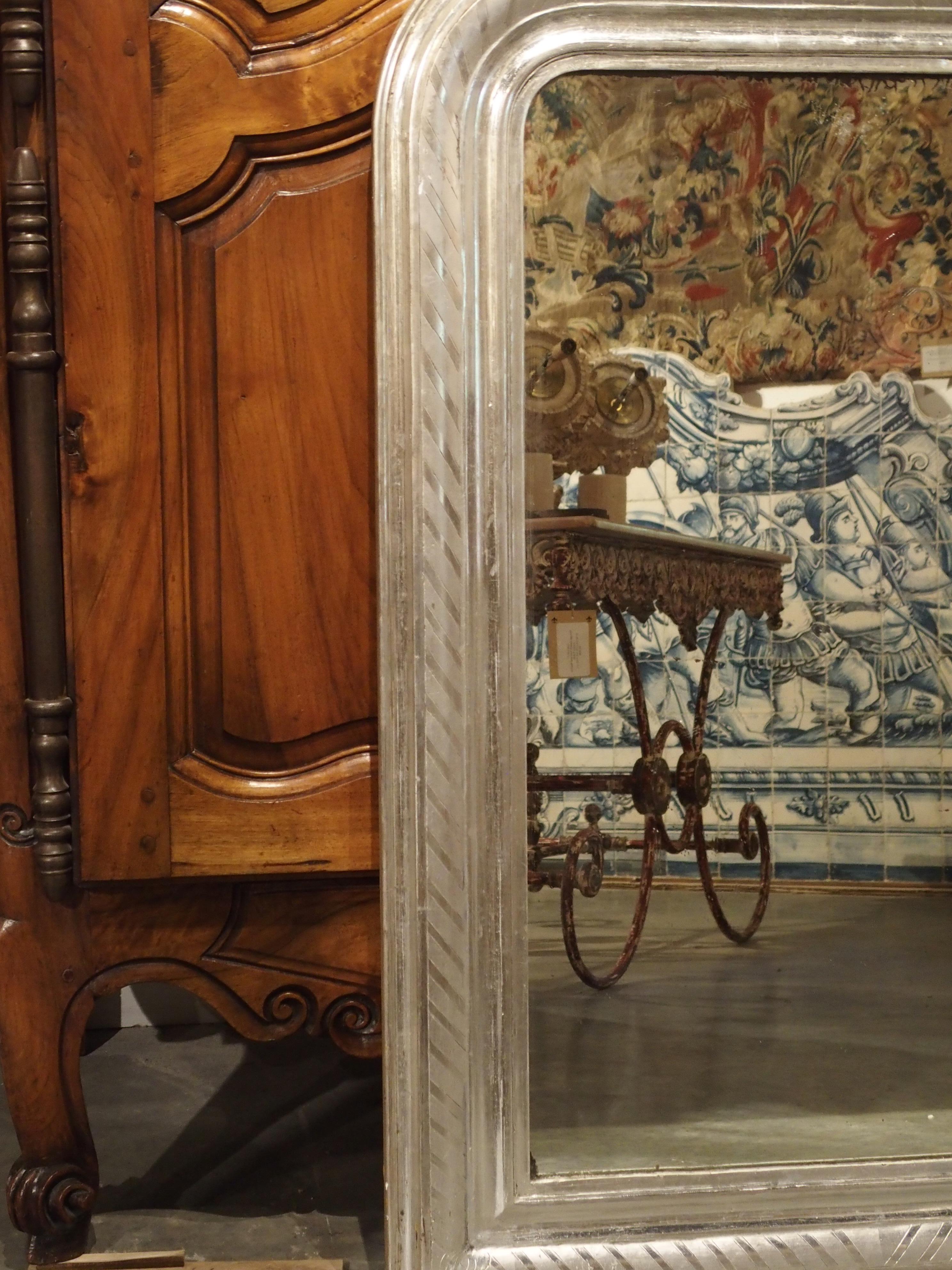 This versatile antique French Louis Philippe has been finished in silver leaf with diagonal rectangles of silver leaf on the raised center molding. There is a plain indented molding above and beneath this center molding. A plain silver leaf molding