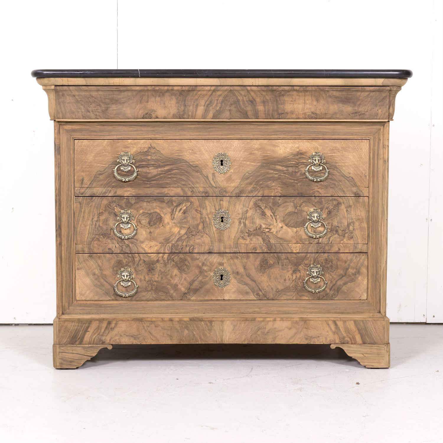 A striking 19th century French Louis Philippe style bleached commode handcrafted of walnut with a bookmatched burled walnut front by talented artisans in Lyon, circa 1870s. Having a beautiful black marble top that rests above a doucine apron drawer