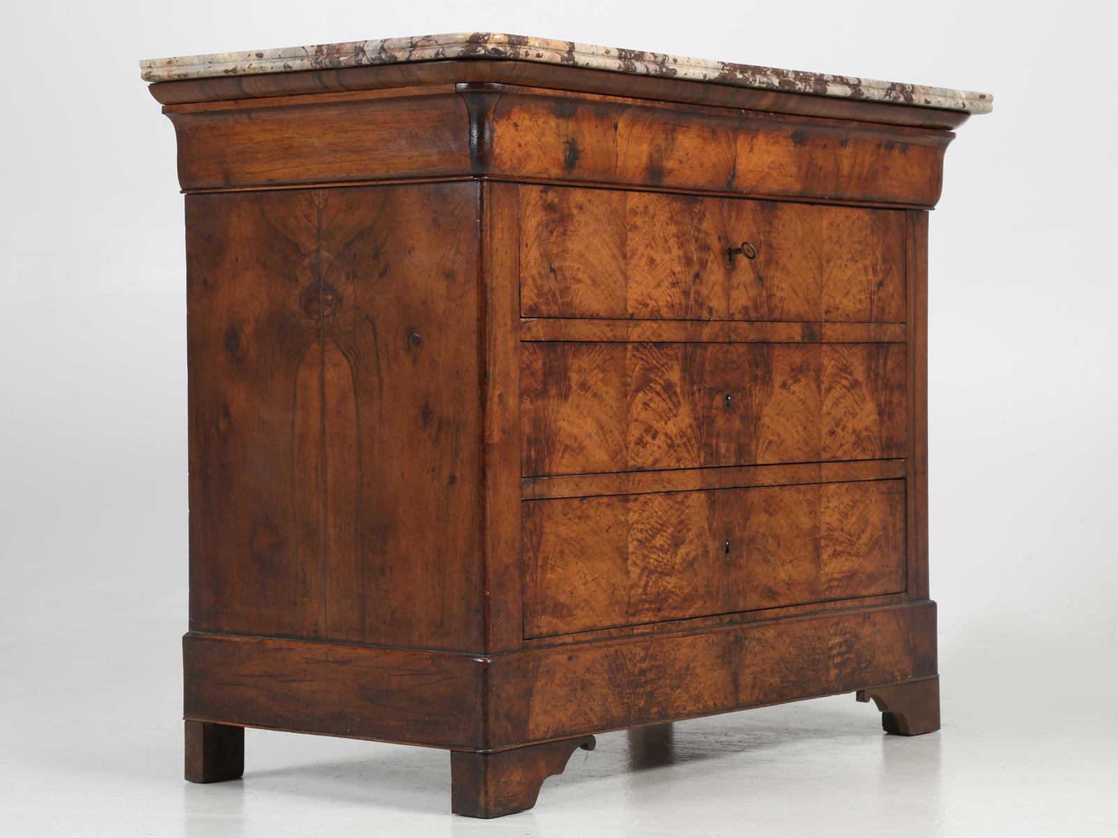 Antique French Louis Philippe style commode, constructed of bookmatched burl walnut, complimented by an exquisite piece of marble, which in itself is extremely rare to find. This particular antique French commode, was discovered in the small town of
