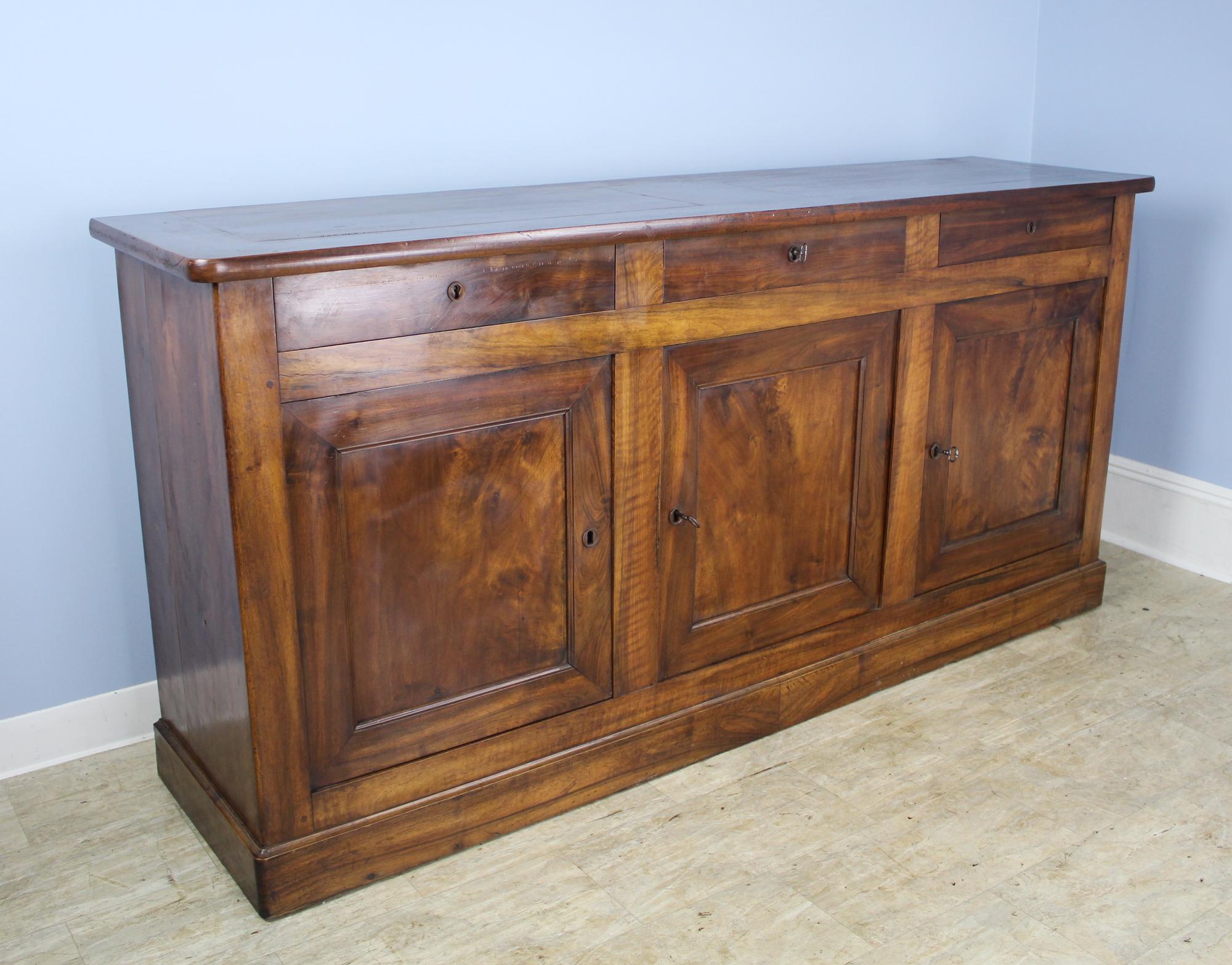 Very handsome console buffet or server, with three cupboard doors and drawers above. The walnut has the typical beautiful light and dark grain and offers a very warm and elegant look. Solid Classic plinth and inset door panels.