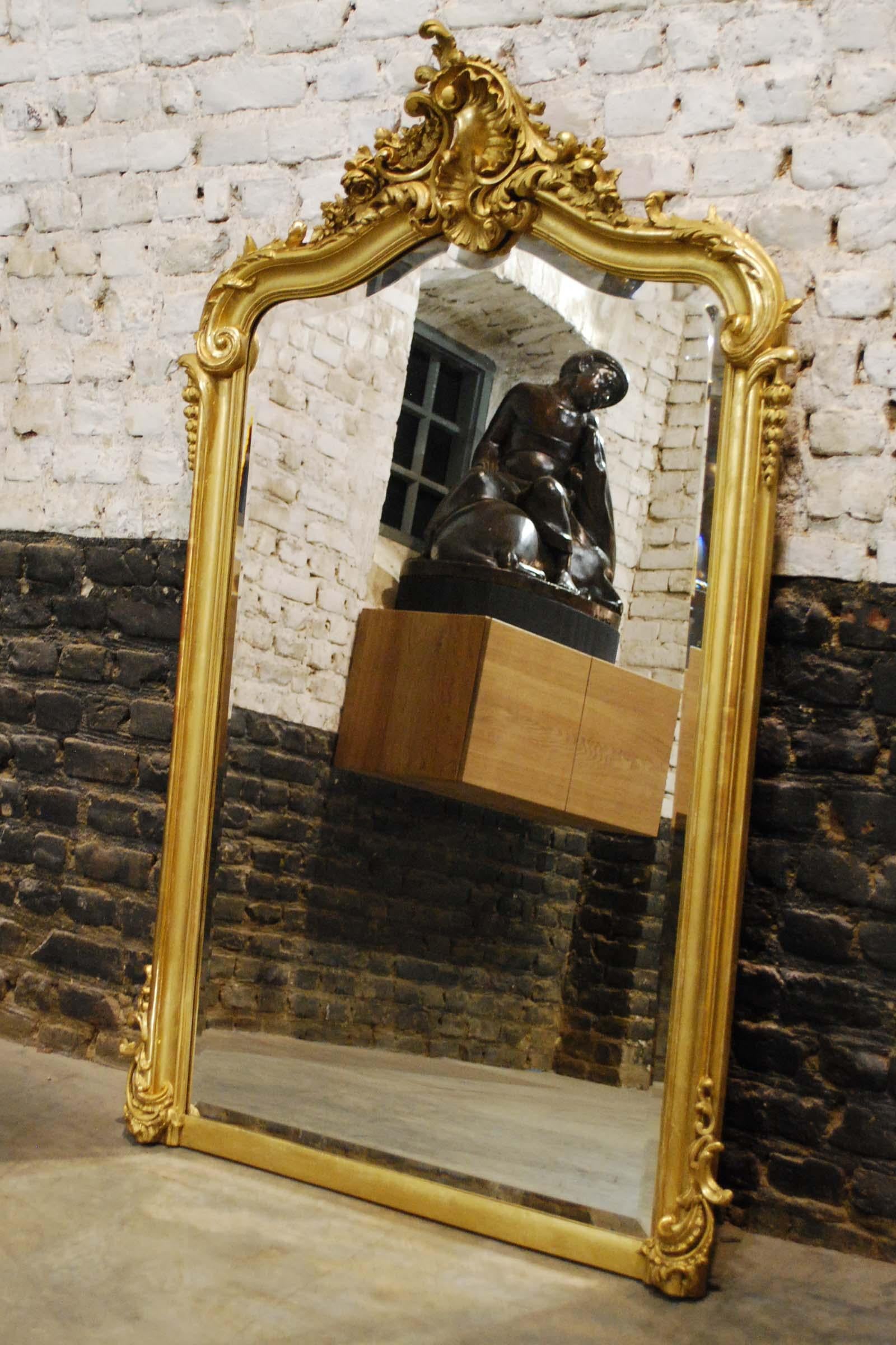 A beautiful antique French mirror in Louis Quinze style. 
It has the asymmetrical ornamentation typical for Louis Quinze and Rococo. The double-arched top features an intricate crown with motifs such as rocailles, shells, flowers, and acanthus