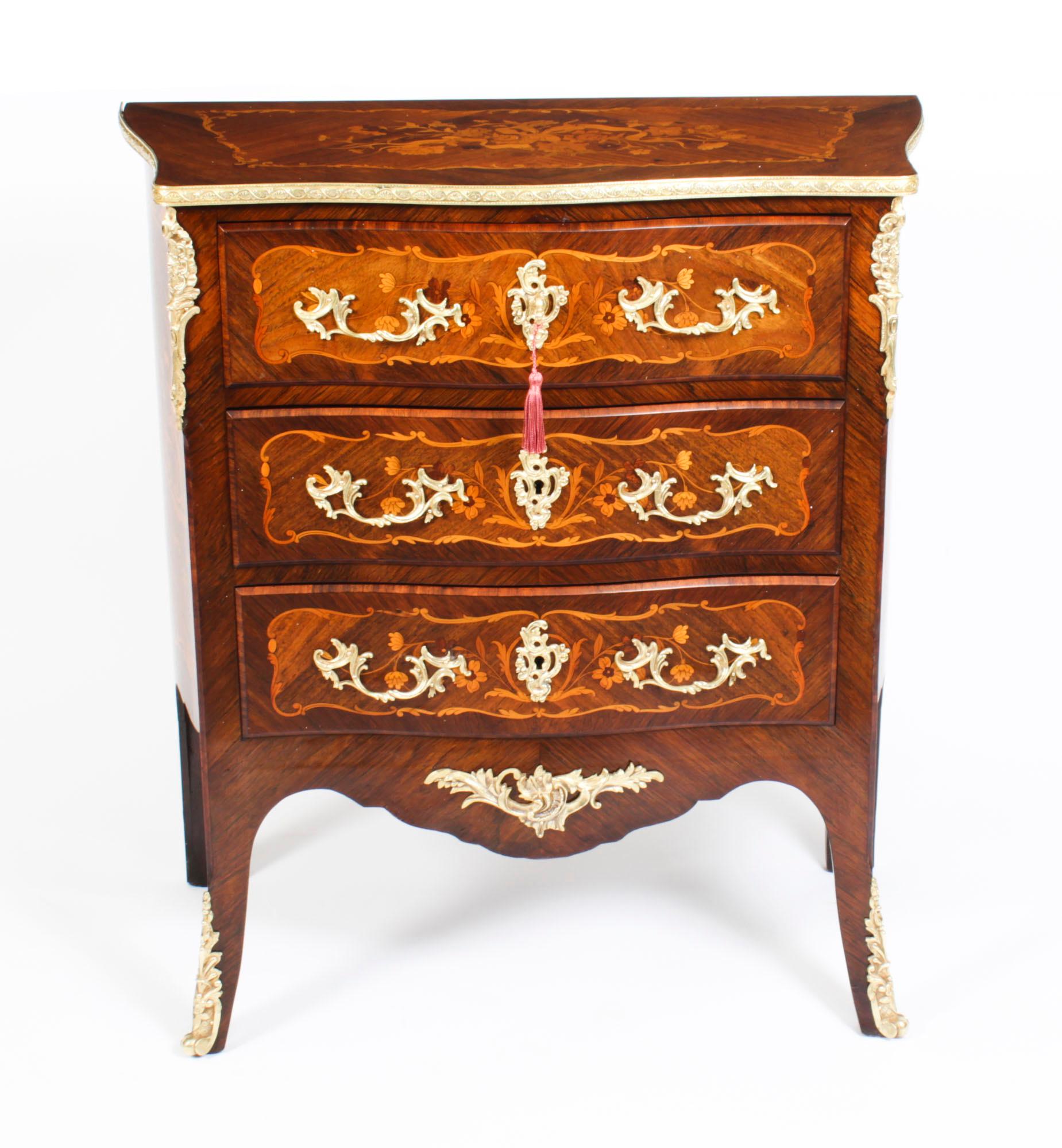 This is a stunning antique walnut, marquetry and ormolu mounted Louis Revival serpentine fronted commode, circa 1880 in date. 
 
The chest has a gonzalo alves cross banded top with decorative ormolu surround, with a central pannel featuring a ribbon