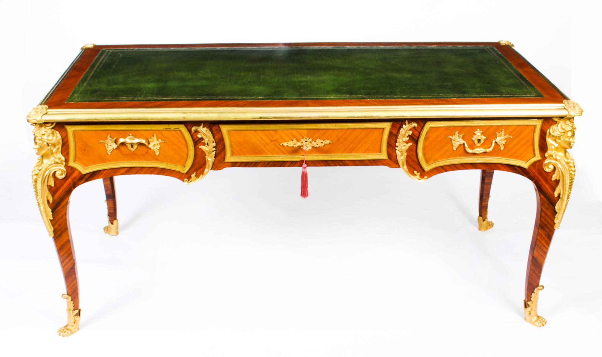 This is a gorgeous antique French Louis Revival gilt bronze mounted amaranth bureau plat, Circa 1880 in date.
 
The rectangular top has a decorative gilt bronze border, raised corner cartouches and a superb inset gold tooled green leather writing