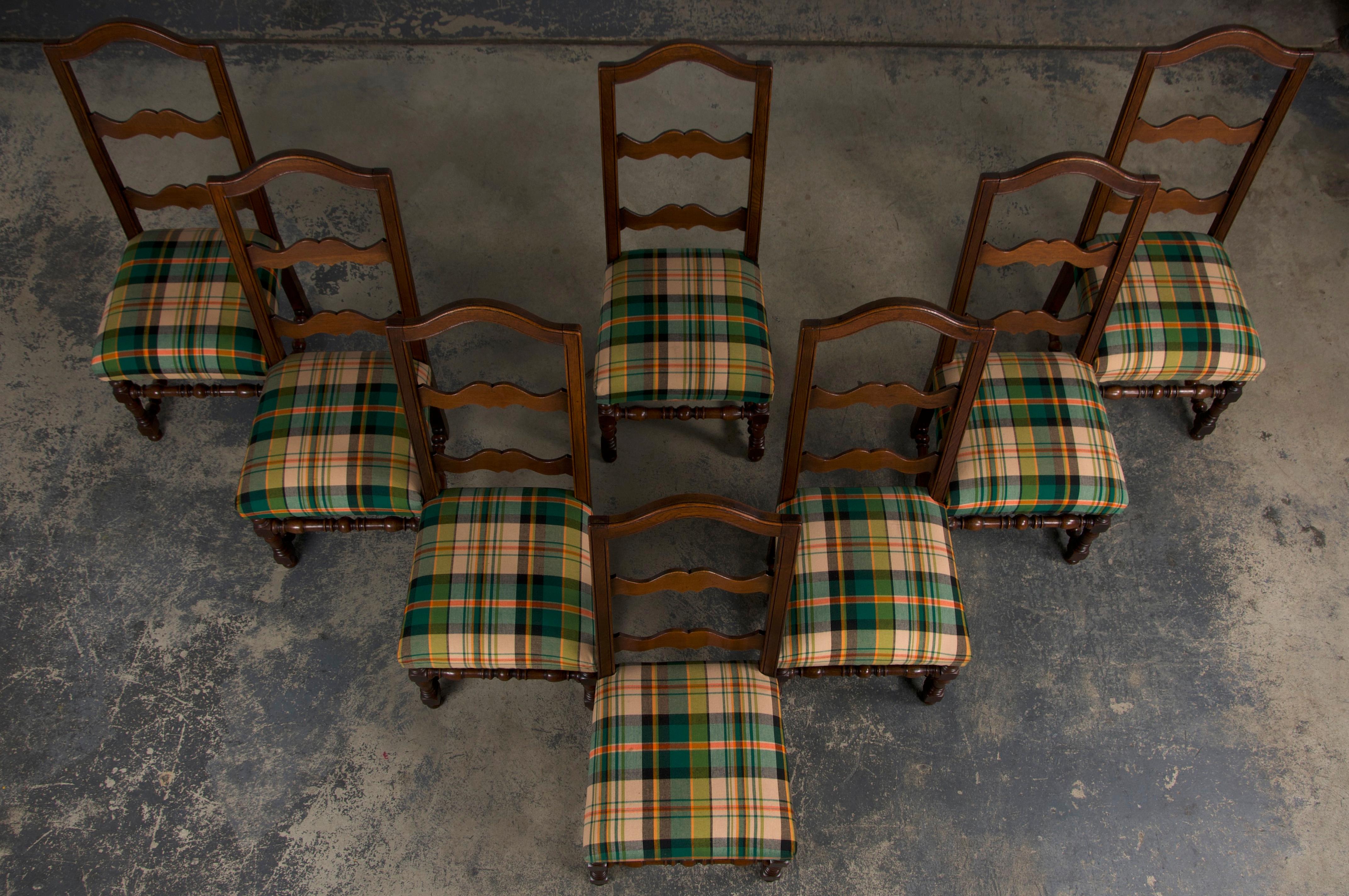 A late 19th-century set of eight French dining chairs in the Louis XIII style, sourced from Provence, France. These chairs are beautifully handcrafted from solid oak, featuring tall ladder-style chapeau de gendarme backs. Structurally restored, they