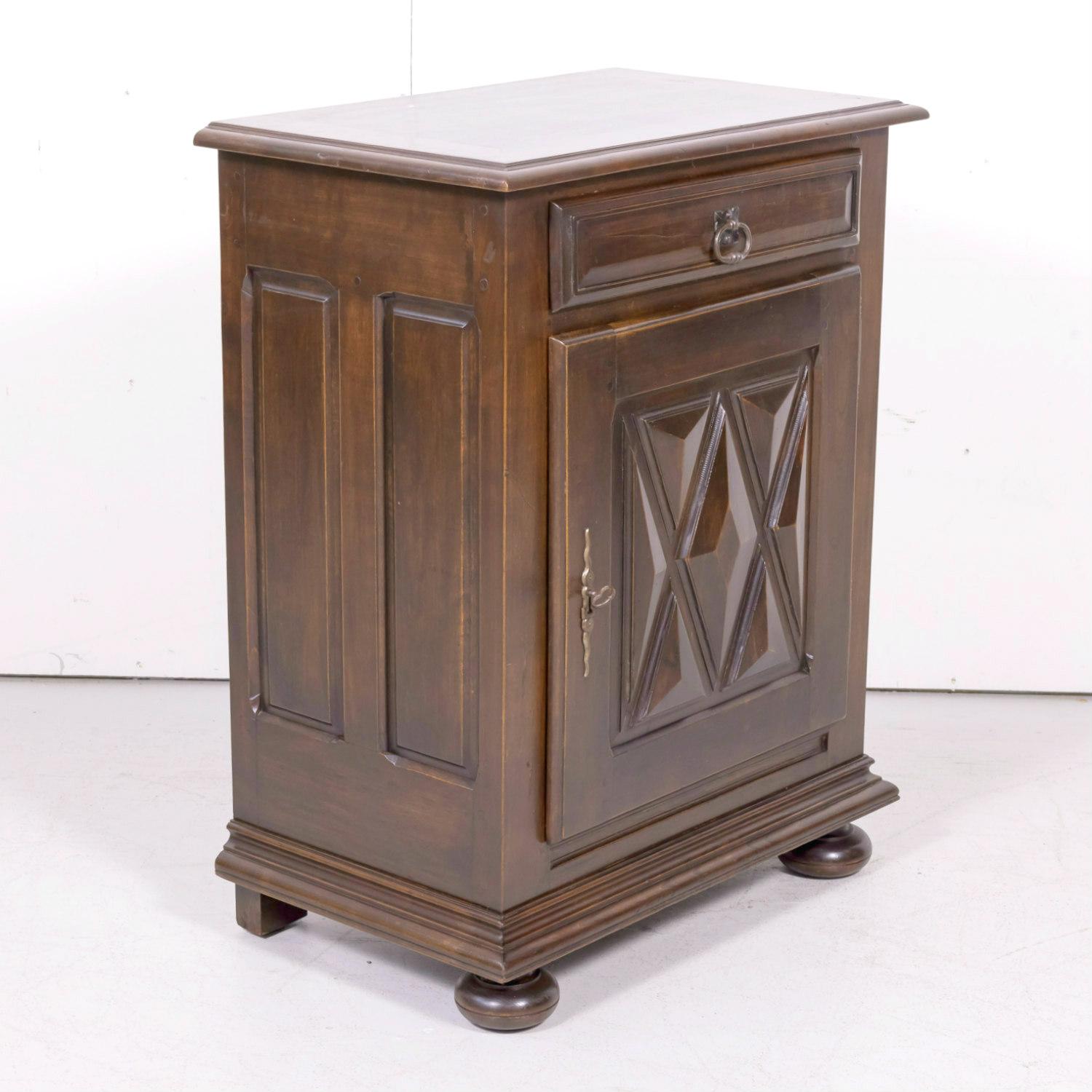 Antique French Louis XIII style confiturier or jam cabinet handcrafted in Brittany of solid walnut with a rectangular beveled edge top over a single drawer above a raised panel door featuring typical Louis XIII style diamante carvings that opens to