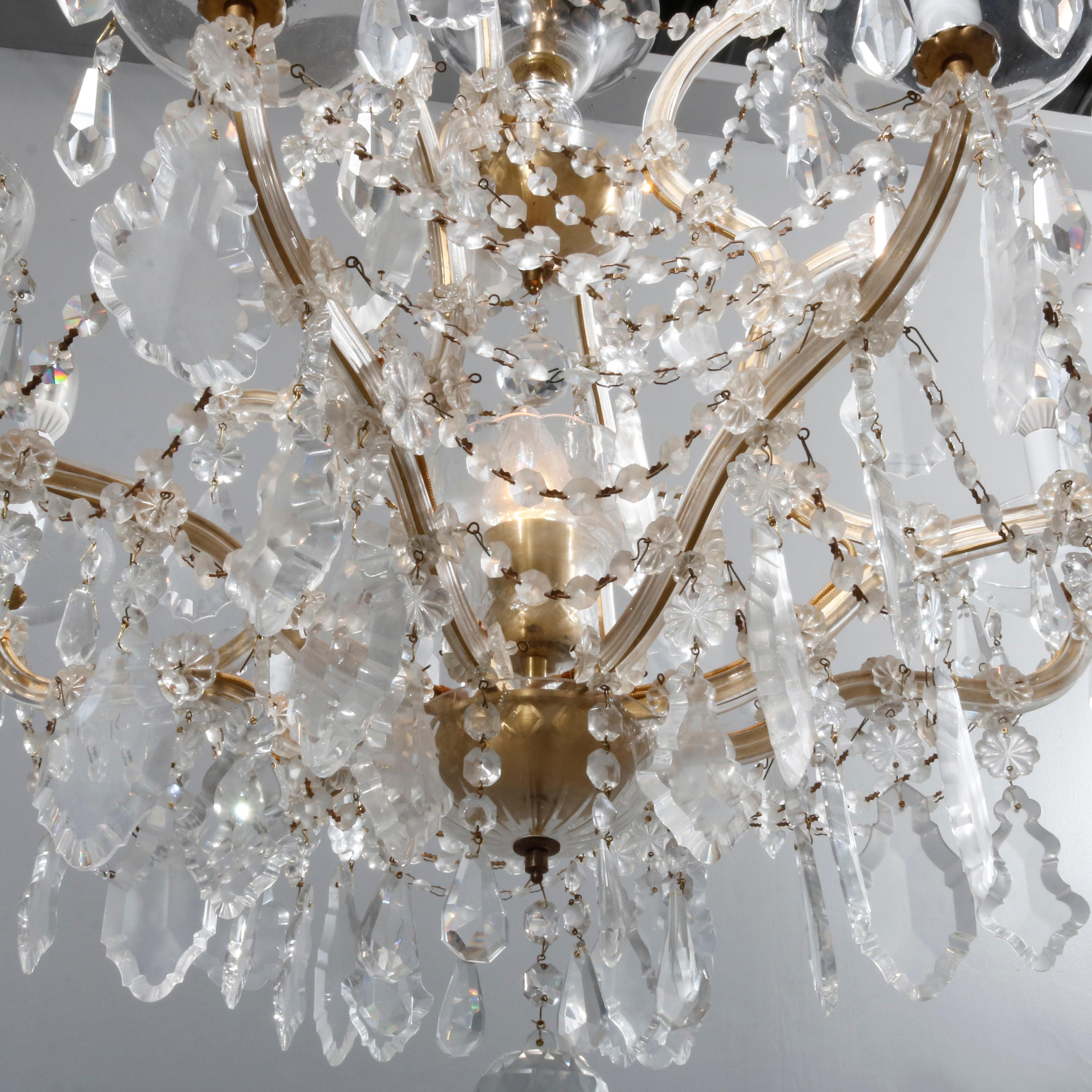 An antique French Louis IV chandelier offers gilt metal frame in scroll form with arms terminating in candle lights, strung and drop cut crystals throughout, professionally wired for US electricity, 20th century

Measures: 47