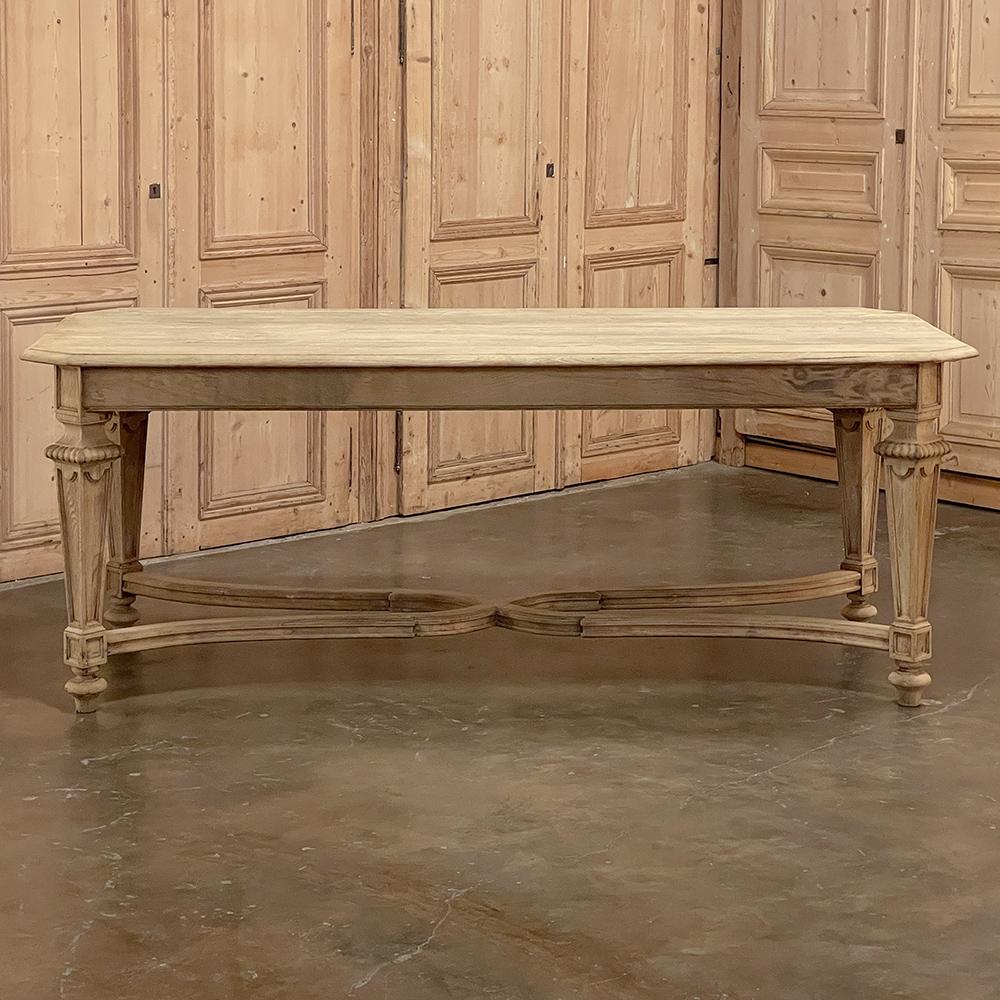 Antique French Louis XIV dining table in stripped oak exudes a stately elegance that is truly understated! The solid oak plank top is beveled on the edge, and mitered on each corner which eliminates sharp edges. The handsome tapered and carved legs
