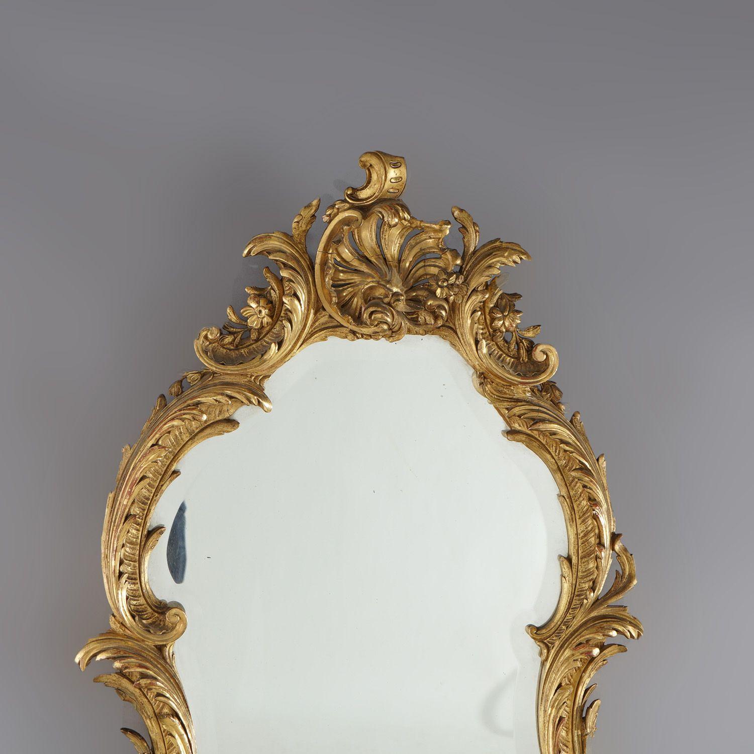 An antique French Louis XIV style wall mirror offers giltwood and gilt plaster construction in foliate form with exaggerated foliate form cartouche, 19th century

Measures - 46.5