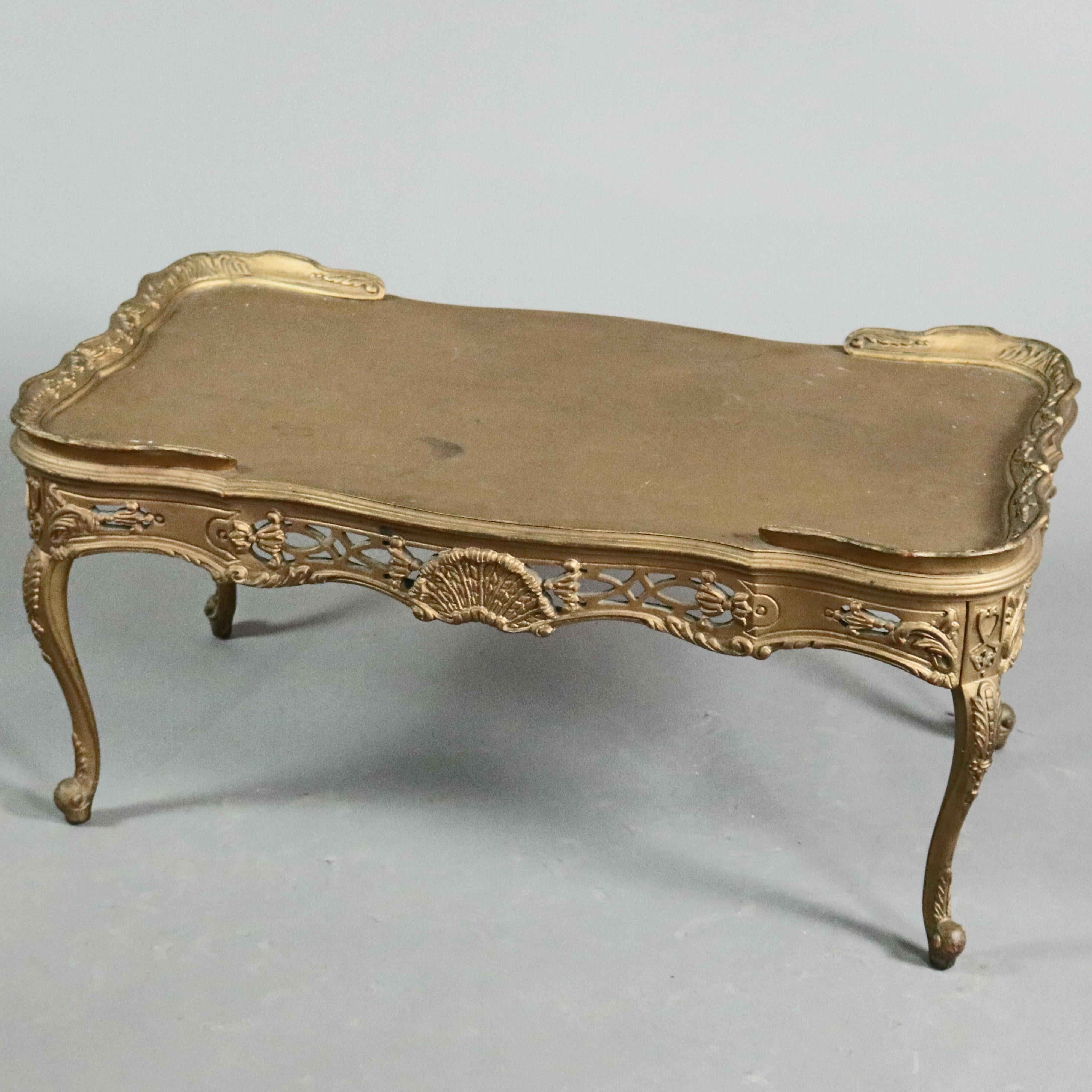 An antique French Louis XIV tea table offers giltwood construction with rimmed and shaped top over pierced shell, scroll and foliate decorated apron, raised on cabriole legs with acanthus knees and scroll feet, 20th century


 Measures: 18