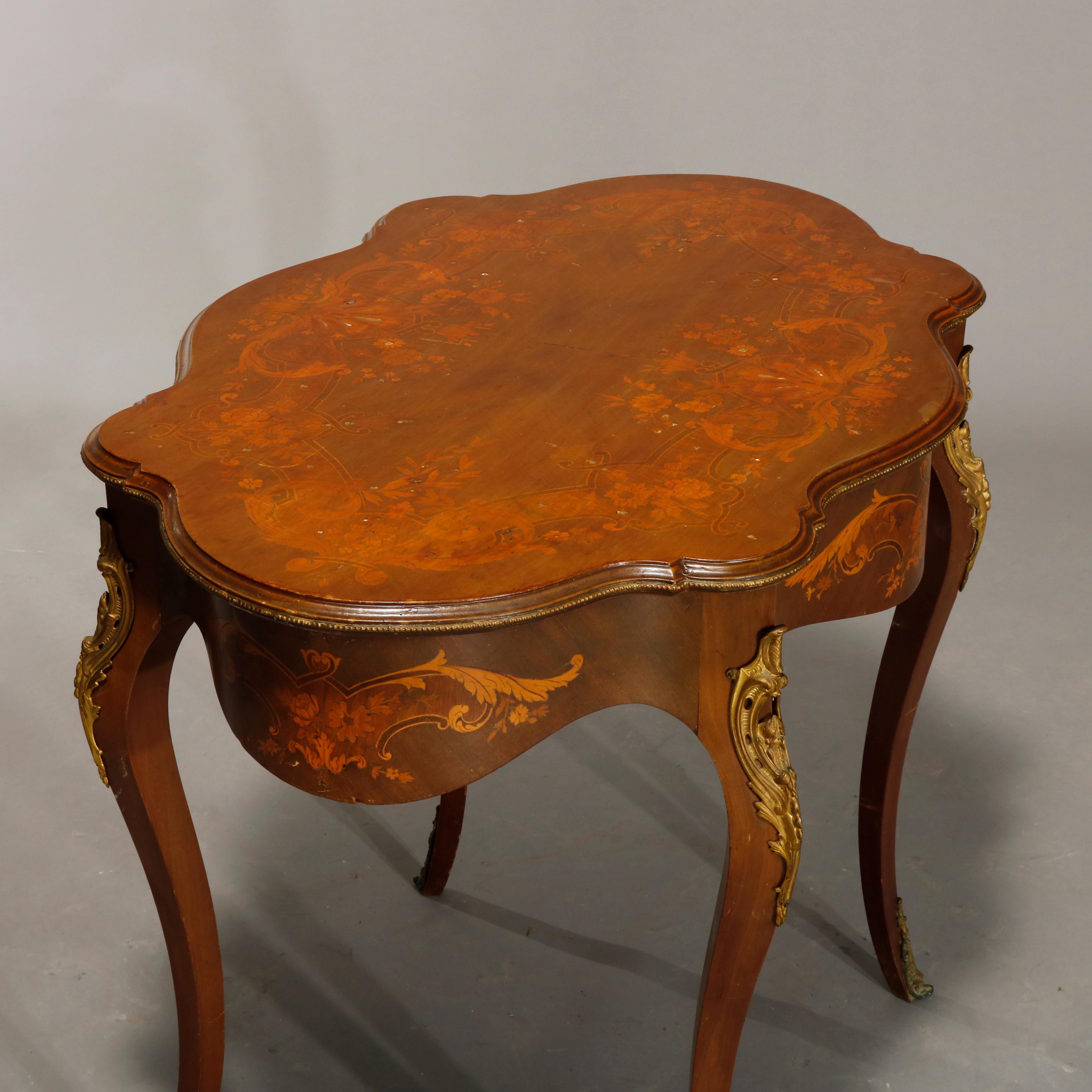An antique French Louis XIV turtle top center table offers mahogany construction with shaped top having satinwood marquetry inlaid top in scroll and foliate design, shaped skirt also having inlaid reserve, raised on cabriole legs having foliate cast