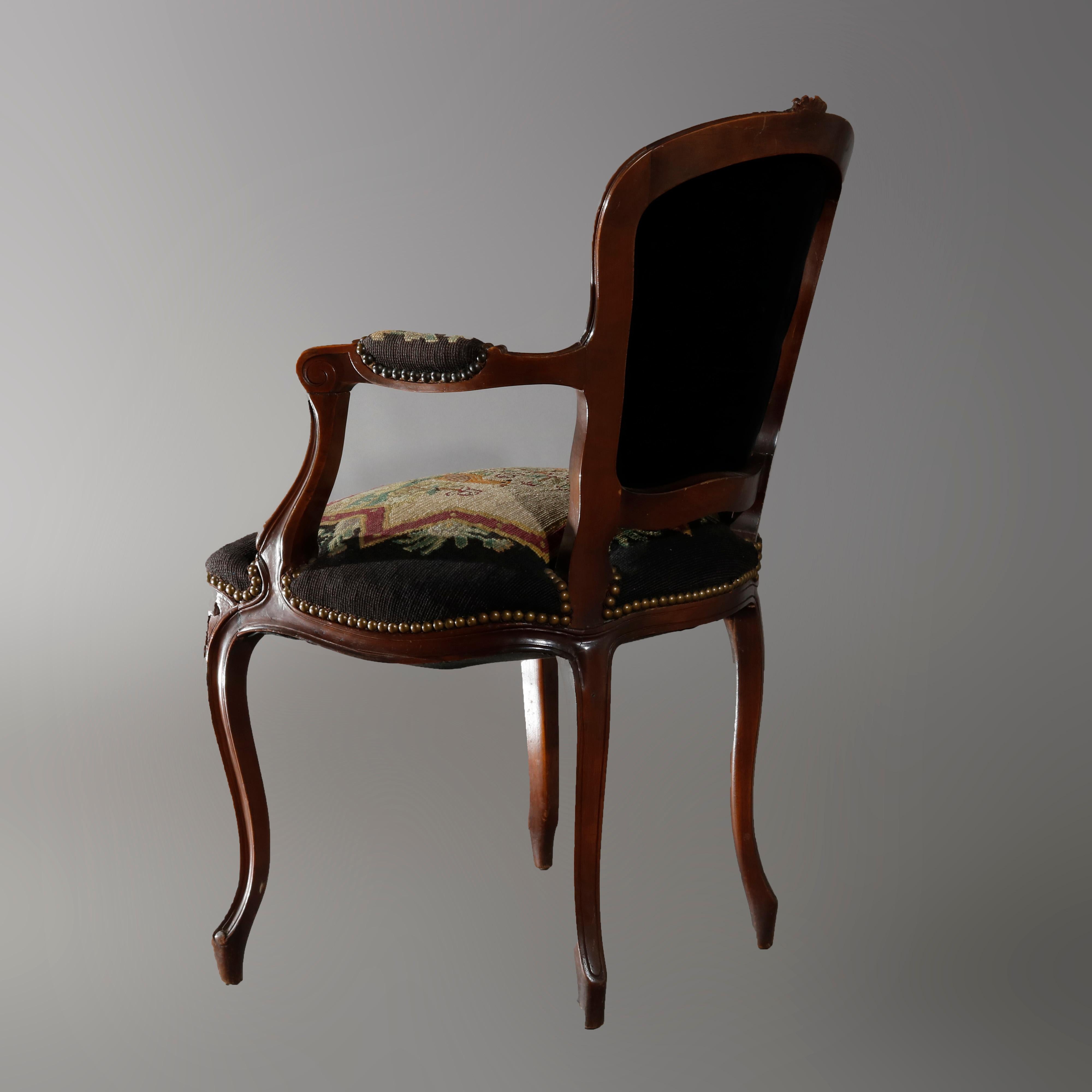 An antique French Louis XIV fauteuil armchair offers walnut frame with foliate carved crest over needlepoint tapestry upholstered back, seat and arms having garden scenes including man and birds, raised on cabriole legs, circa 1920

Measures: