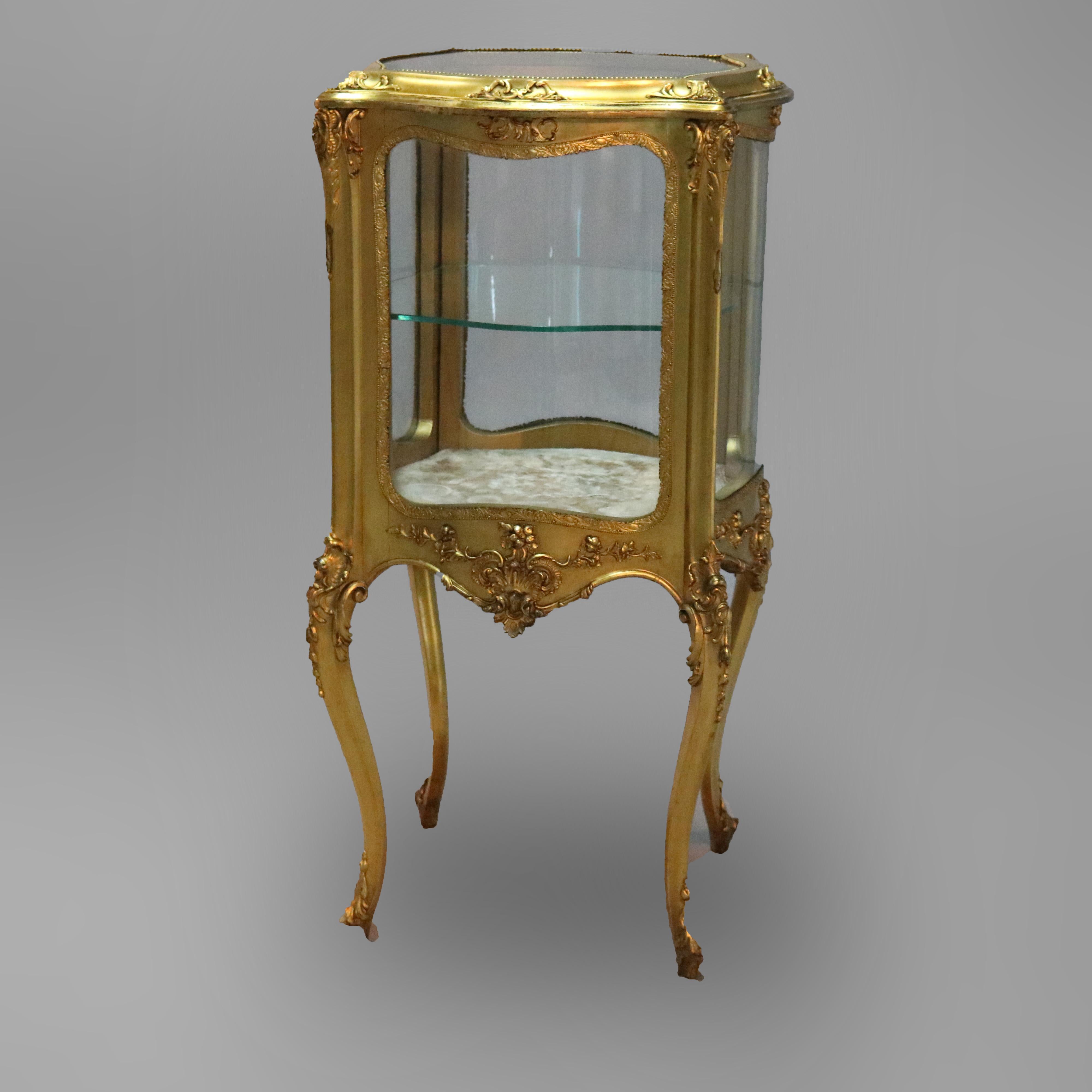 An antique French Louis XIV vitrine offers giltwood construction in serpentine form having a single door opening to shelved interior display, scroll and foliate elements throughout and raised on cabriole legs terminating in acanthus feet, circa