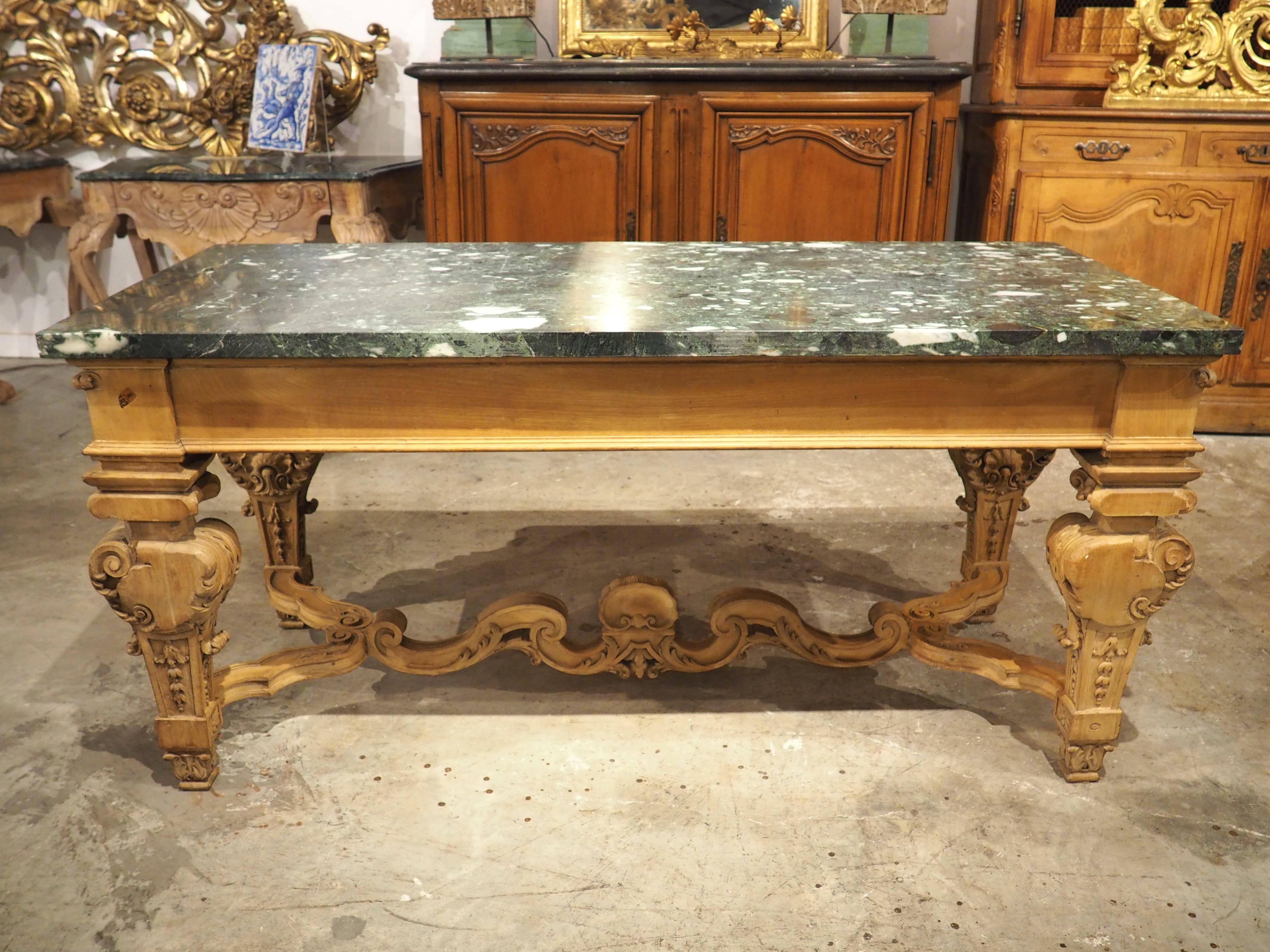 A fantastic table from France, circa 1880, this console has been hand-carved with motifs in the style of Louis XIV. The beautiful blonde walnut wood was carved by a master-level ebeniste, as noted by the delicate foliate latticework surmounted by a