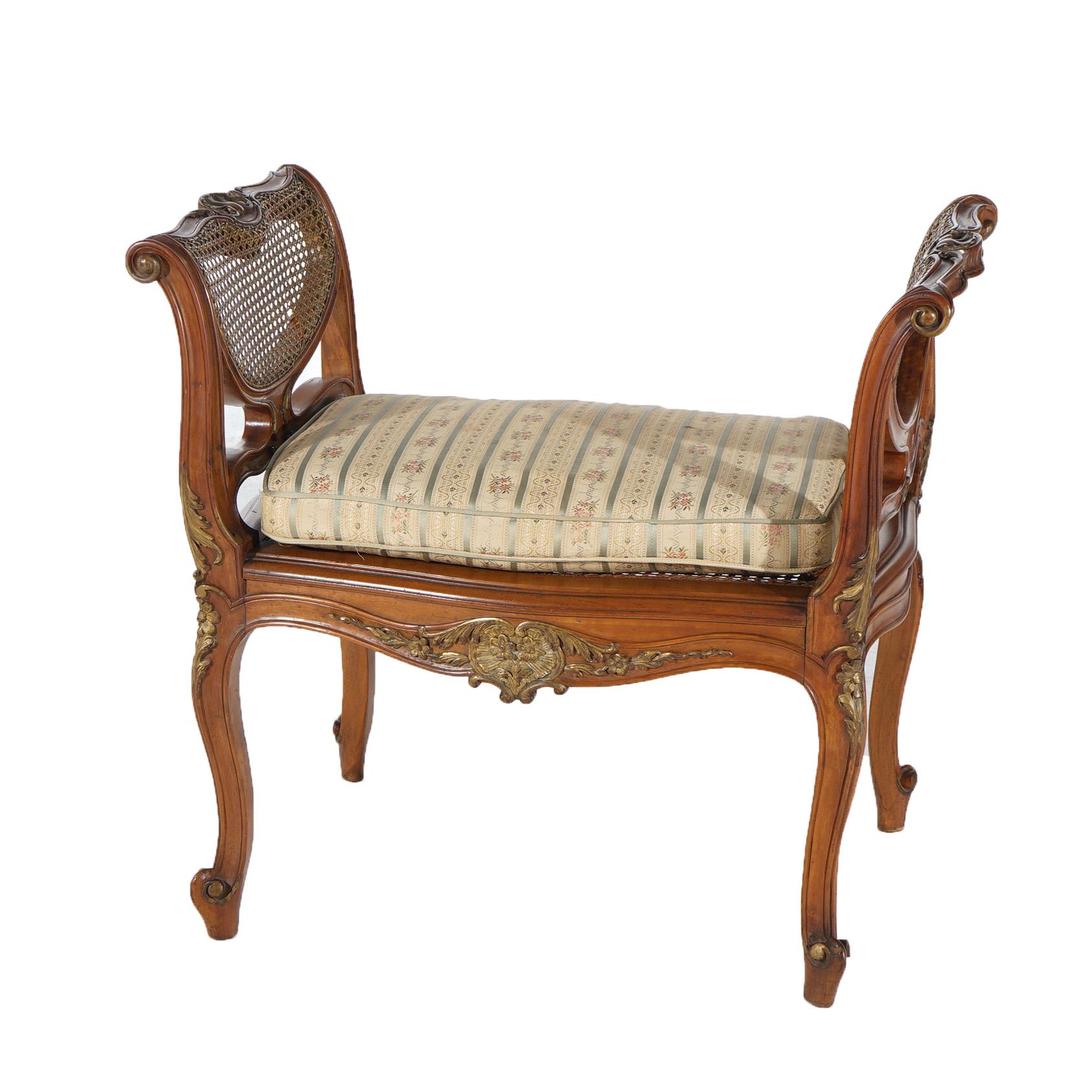 ***Ask About Discounted In-House Shipping***
An antique French Louis XIV style window bench offers walnut construction with carved gilt floral elements, caned arms, upholstered seat and raised on cabriole legs terminating in scroll feet,