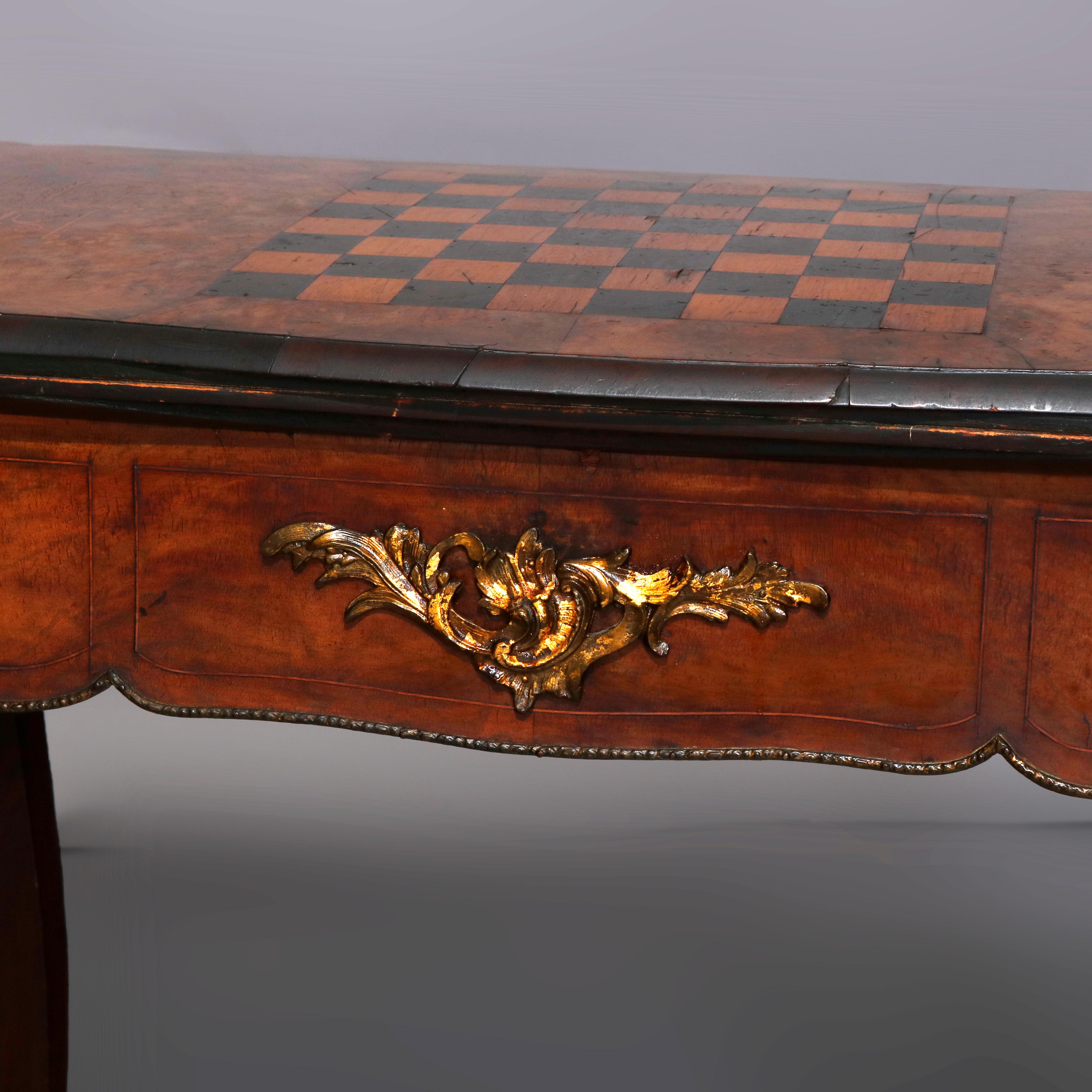 An antique French Louis XIV style game table offers walnut and burl construction with shaped top having chess and checker board with flanking satinwood scrolled foliate marquetry and opening to felted card table over deep skirt raised on cabriole